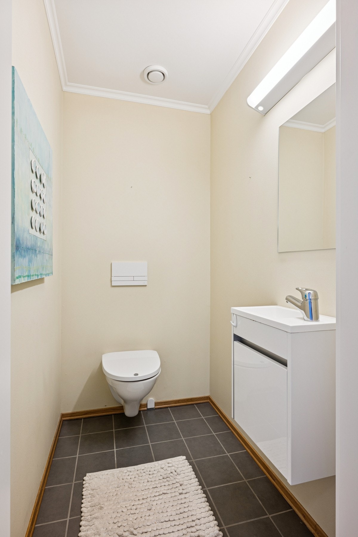 Separat toalettrom med vegghengt toalett, servant og speil - praktisk og stilrent. Galleribilde