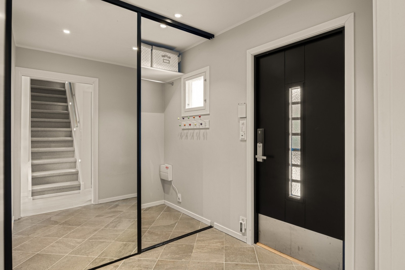 Romslig entrè med fliser med gulvvarme og stor skyvedørsgarderobe. Galleribilde