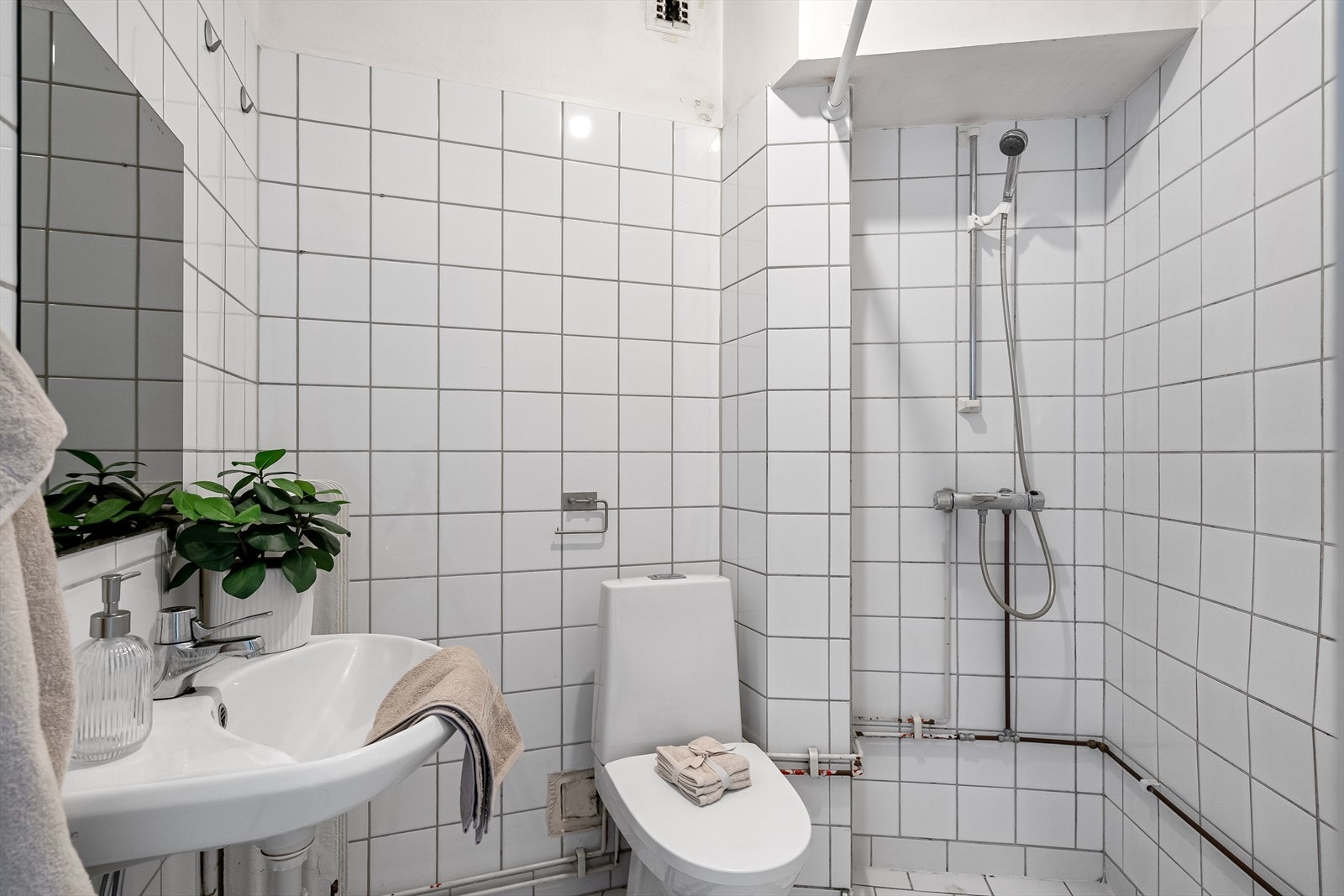 Flislagt bad utstyrt med dusjnisje, naturlig avtrekk, servantskap og wc Galleribilde
