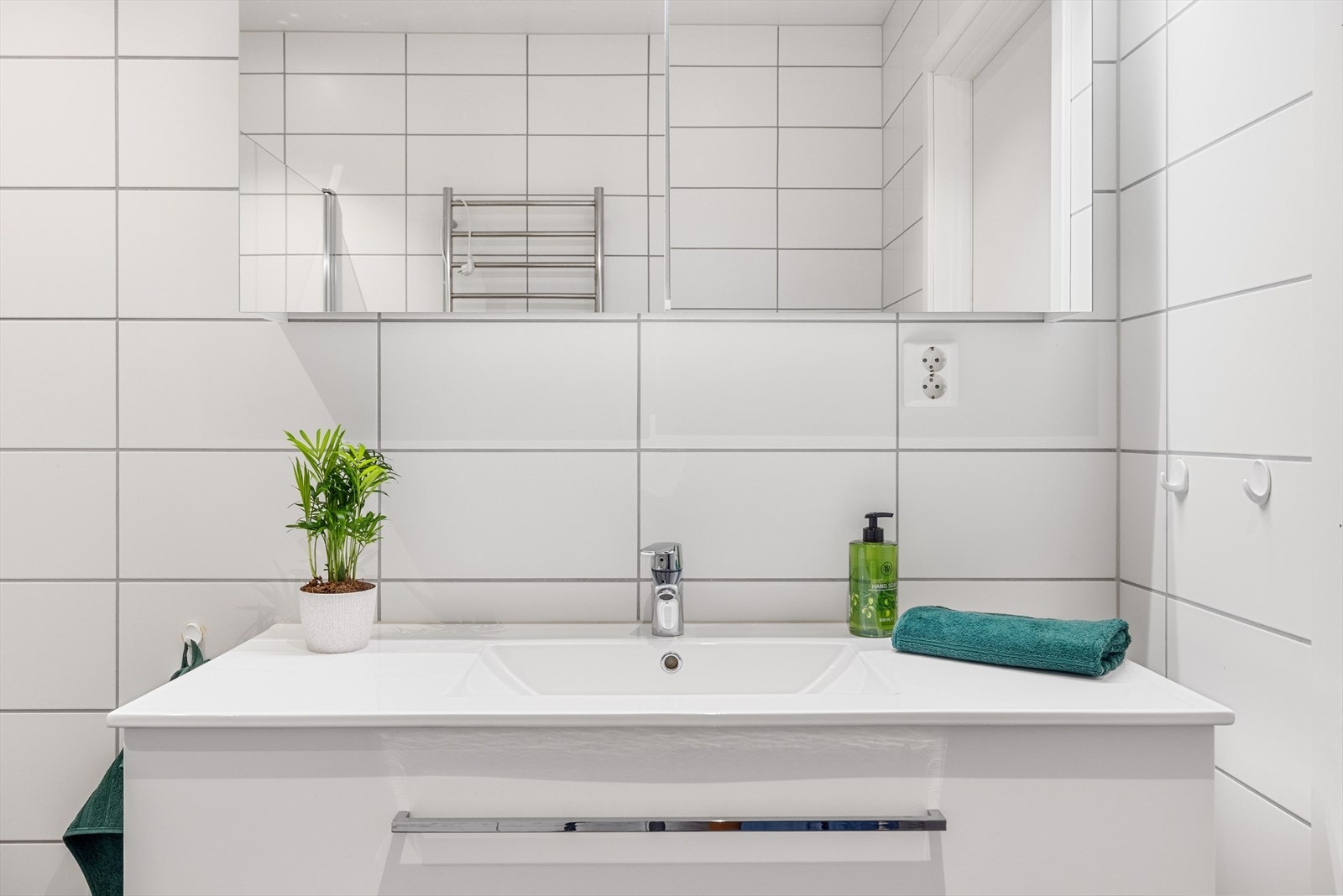 Moderne baderomsinnredning med skuffer og heldekkende servant, speilskap med belysning over. Galleribilde