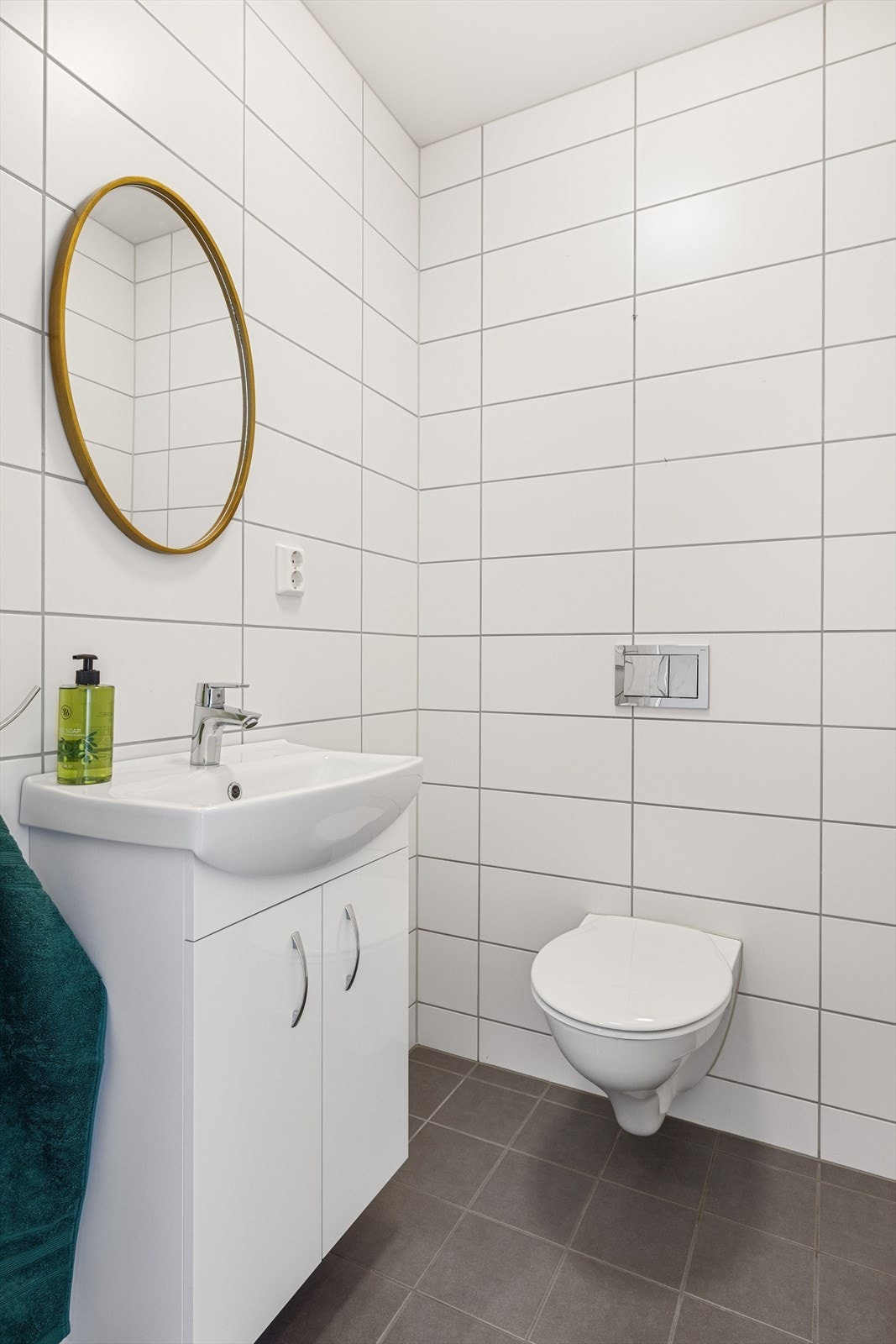 Boligen har også et praktisk ekstra toalettrom fra 2020. Toalettrommet har mørke fliser på gulv, hvite fliser på veggene, og er utstyrt med servantskap og vegghengt toalett. Galleribilde