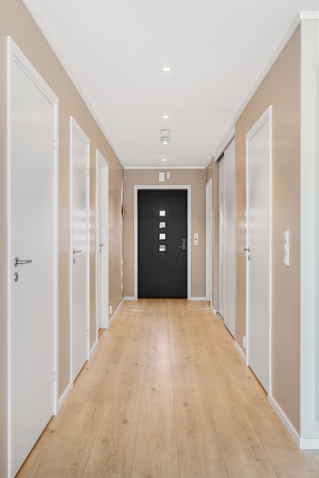 Entréen har pen enstavs laminat med gulvvarme, plater på veggene malt i en nydelig farge og downlights i himlingen. Rikelig med oppbevaringsplass i stor plassbygget skyvedørsgarderobe med lyse dører. Galleribilde