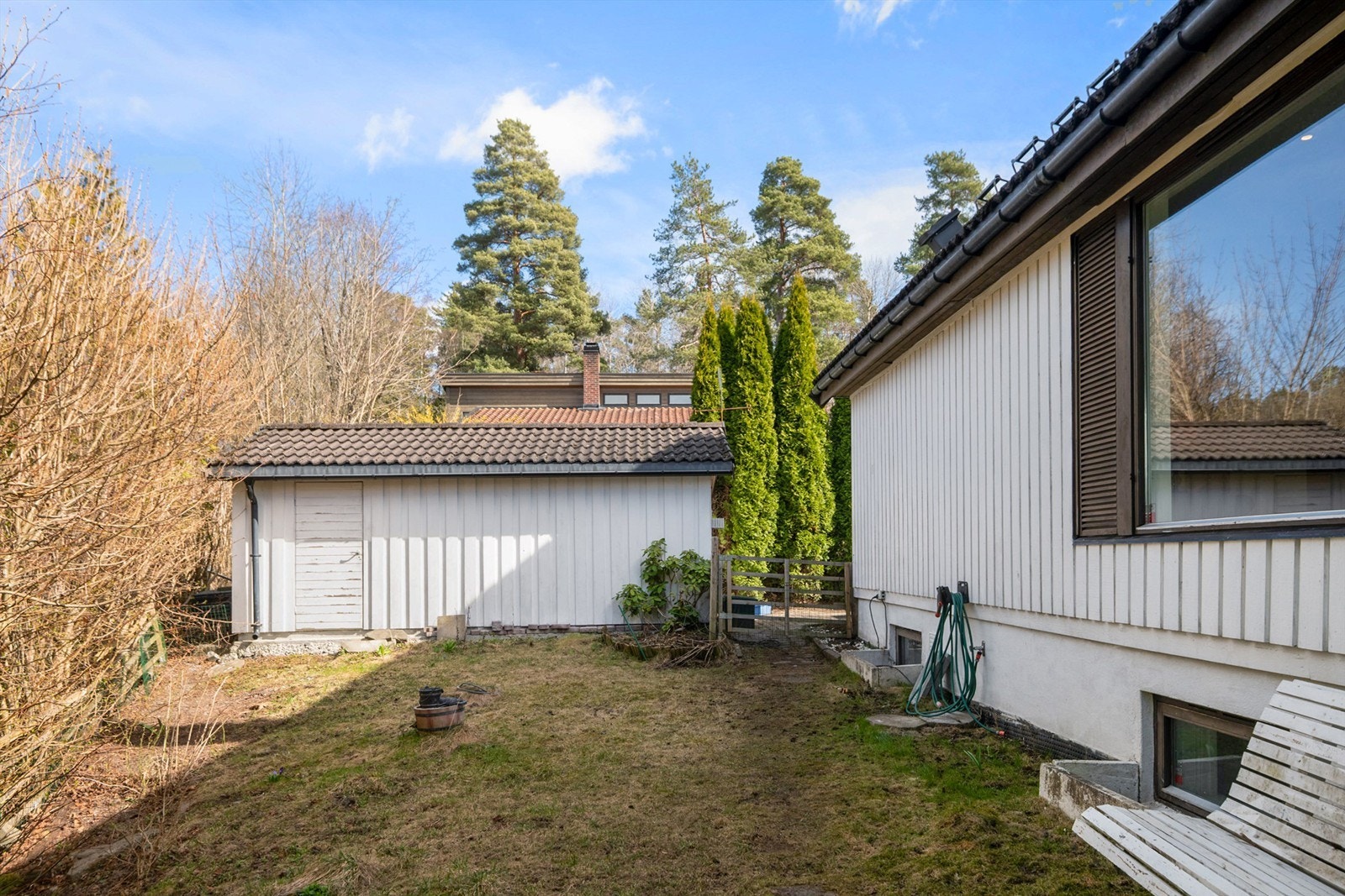 Hagen på nordsiden av huset mot tihørende garasje. Galleribilde