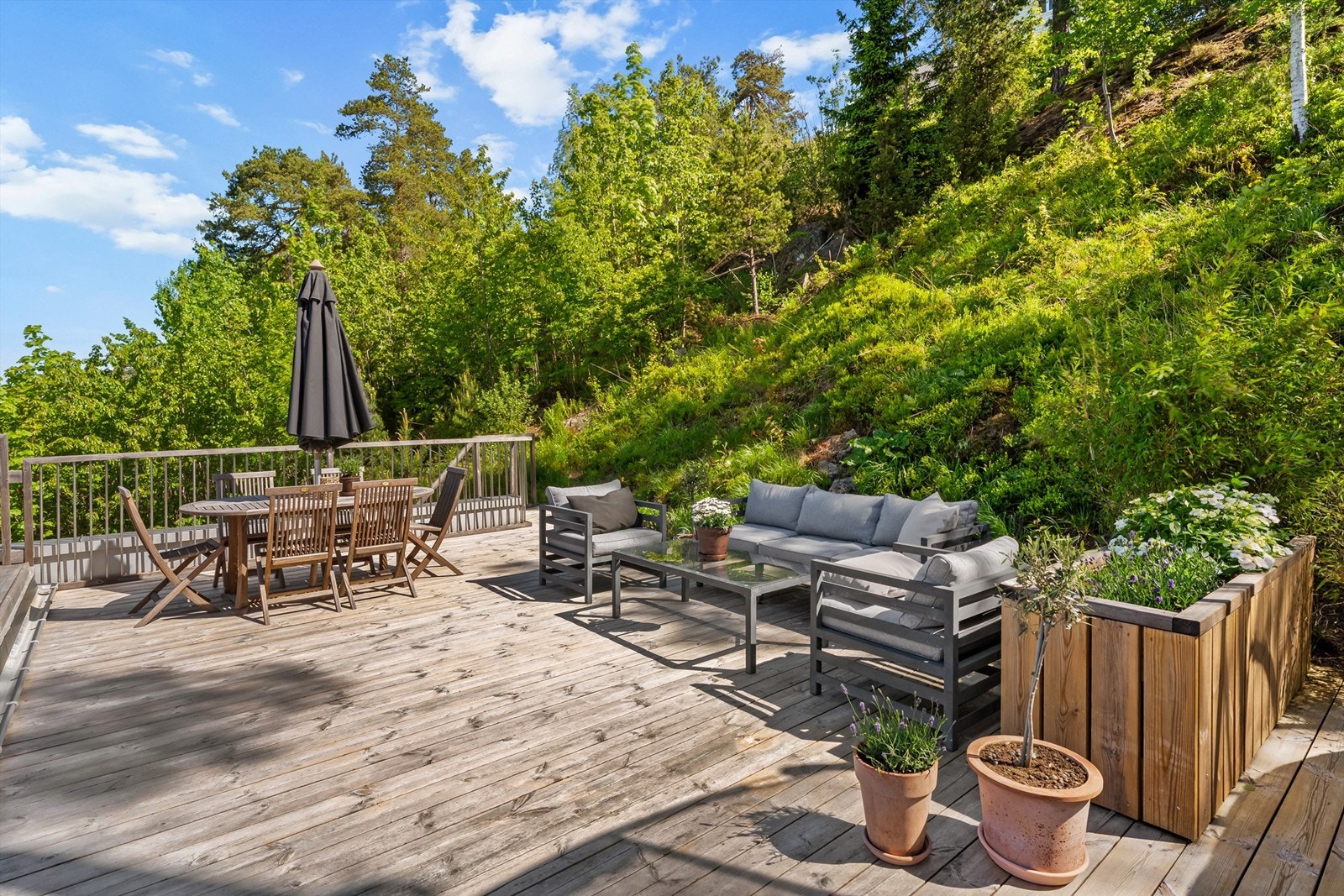 Her kan du kan enkelt møblere i soner etter ønsker og behov - skrående naturtomt og rekkverk av Kebony med rustfrie stål spiler Galleribilde