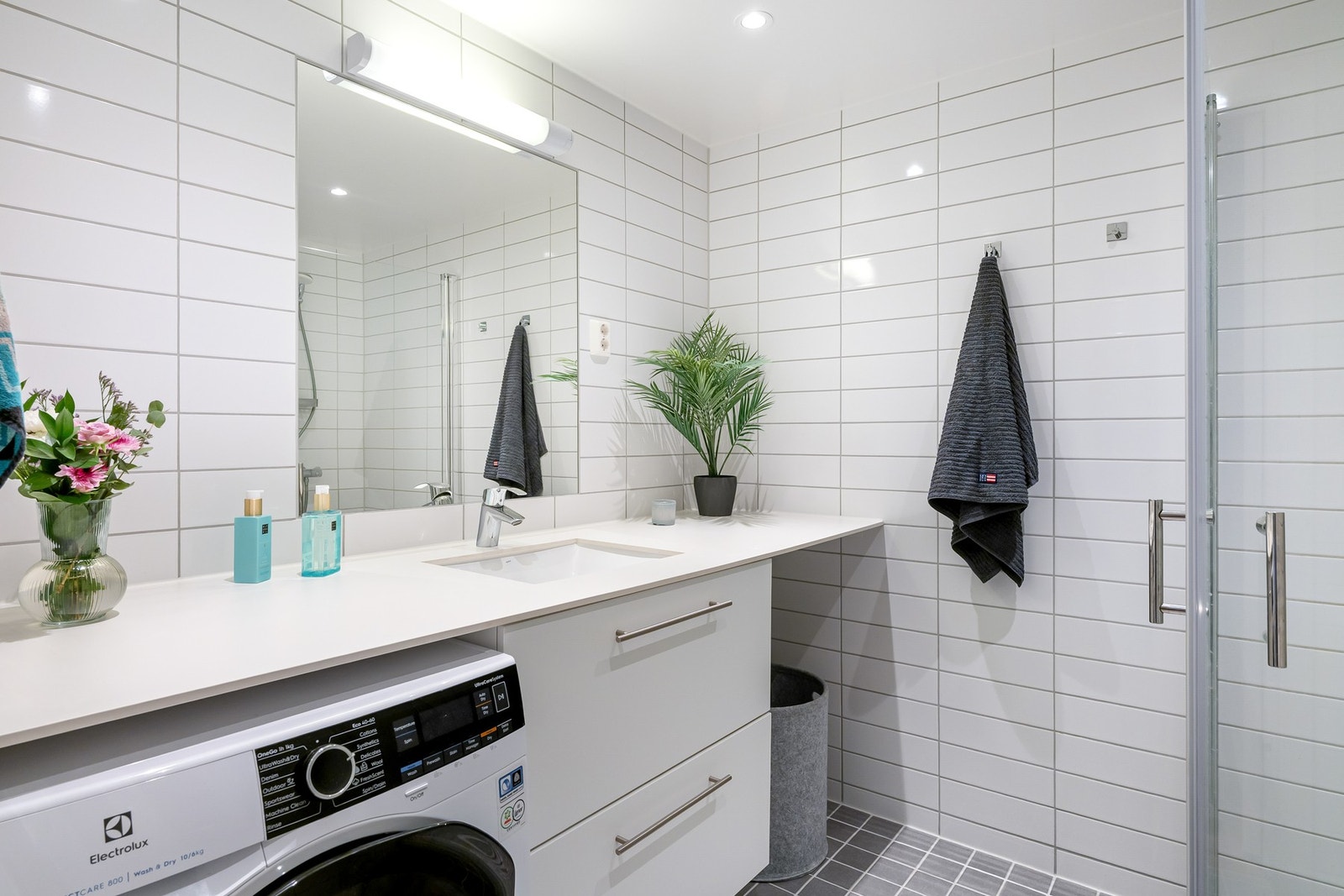 Det flotte, flislagte baderommet ligger i tilknytning til entréen. Videre er det dusjnisje, servant med skuffer og opplegg for vaskemaskin. Galleribilde