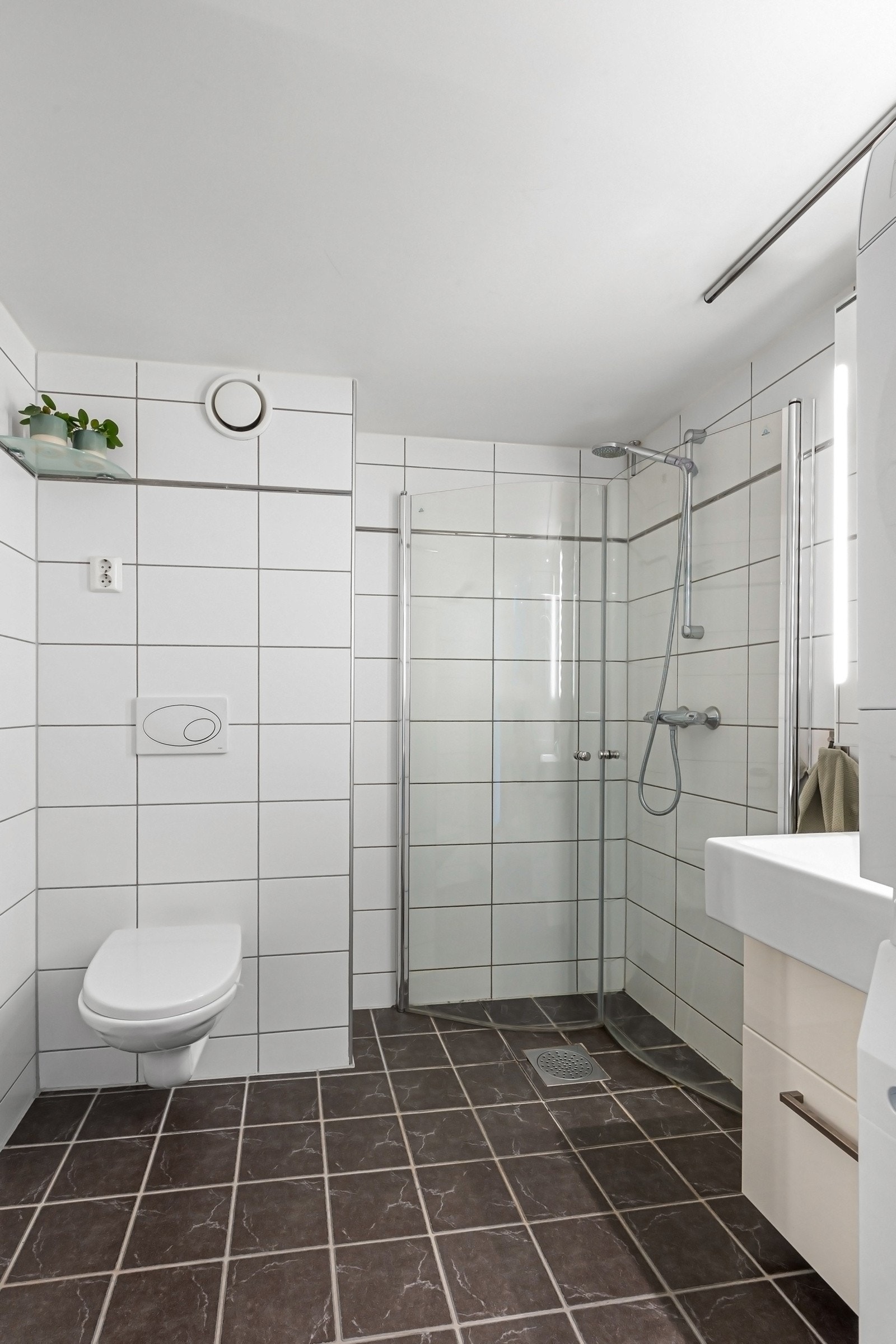 Leiligheten har et pent bad med flislagte overflater og downlights i himling Galleribilde