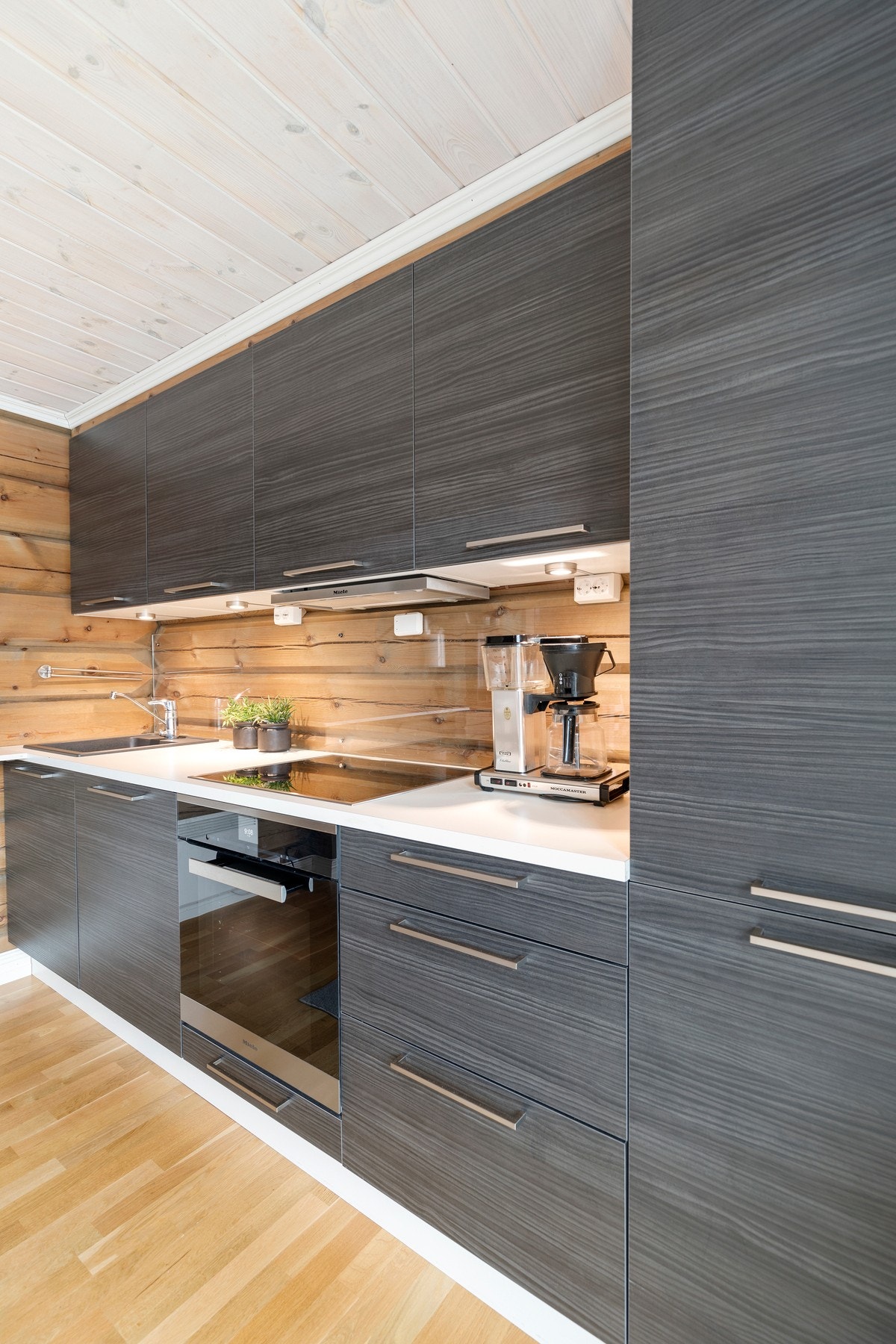 Kjøkkenet har innredning fra HTH som er utstyrt med sorte, slette fronter, laminat benkeplate med glassplate mot overskap, ventilator og belysning under overskapene. Videre inneholder kjøkkeninnredningen følgende integrerte hvitevarer; oppvaskmaskin, stek Galleribilde