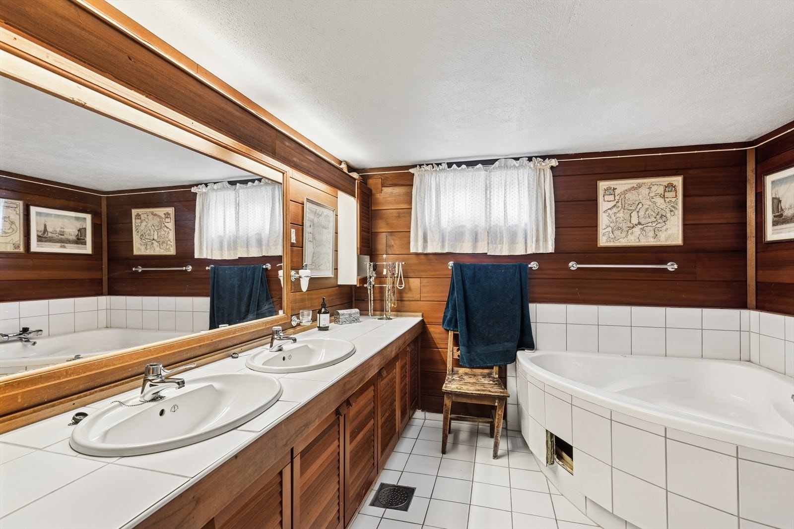 Eldre bad med fliser på gulv, fliser og panel på vegger, standard innredning, støpejernsluk, dusjhjørne og hjørnekar. Galleribilde