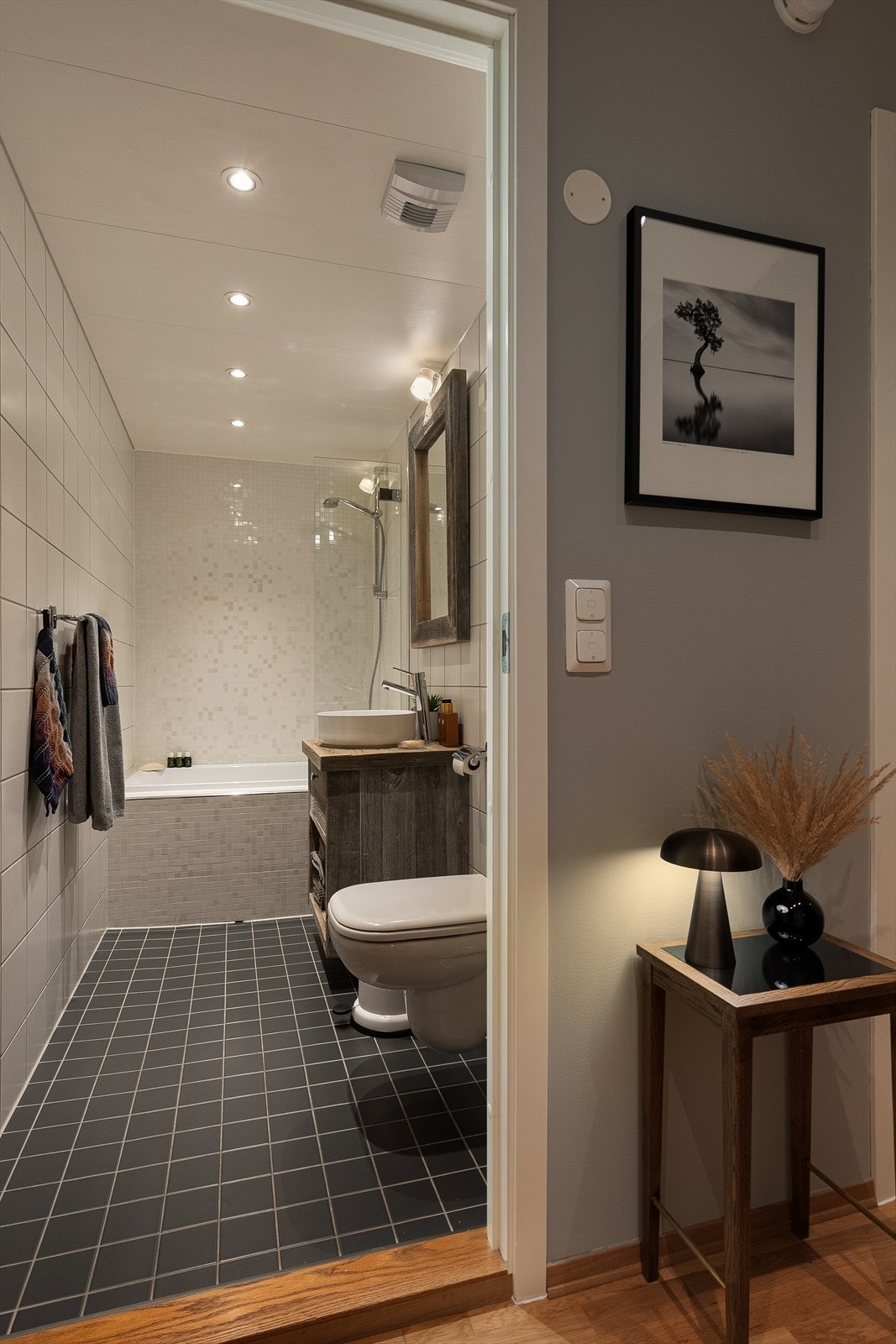 Lekkert baderom med varmekabler på gulv. Badekar og vegghengt klosett. Galleribilde