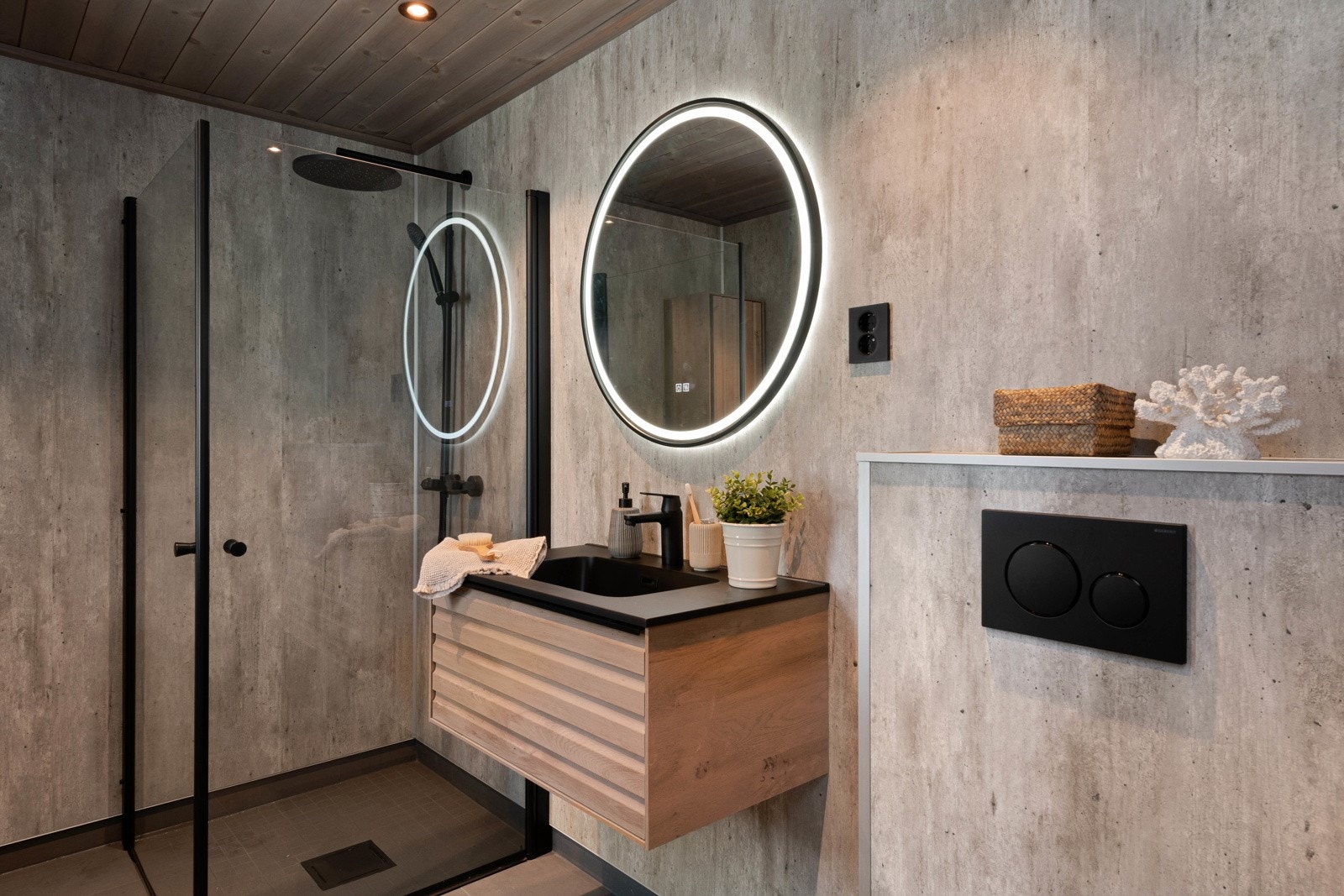 Badet er stilig utformet, lettstelt og moderne med mørke fliser på gulvet, betongfargede baderomsplater på veggene, gulvvarme og beiset panelhimling med downlights. Galleribilde