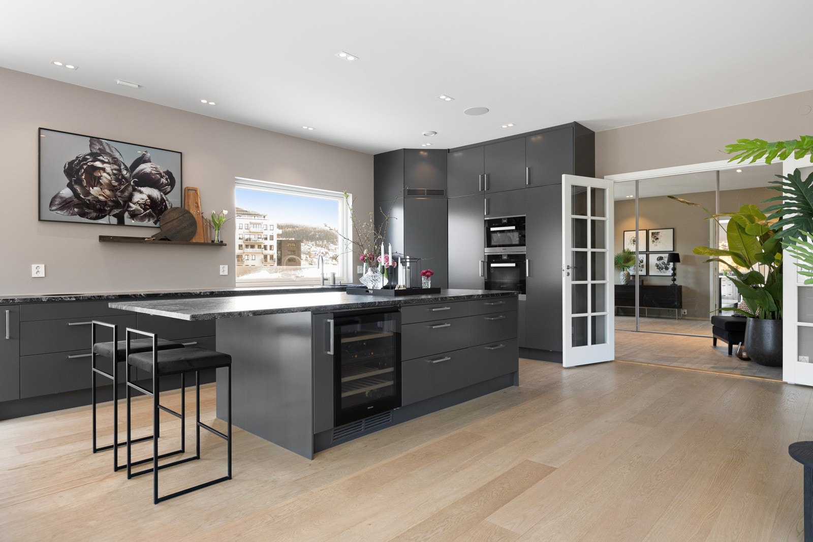 Den romslige kjøkkenøya med integrert vinskap og kjøleskuff gir både praktisk oppbevaring og en sosial sone for matlaging. Galleribilde