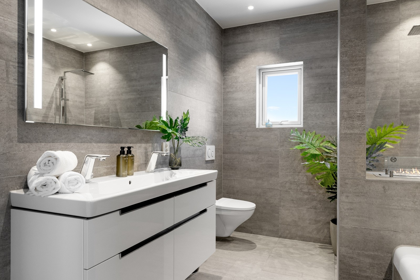 Dette stilfulle badet har flislagte vegger og gulv, gulvvarme og taket er malt i en moderne farge. Galleribilde