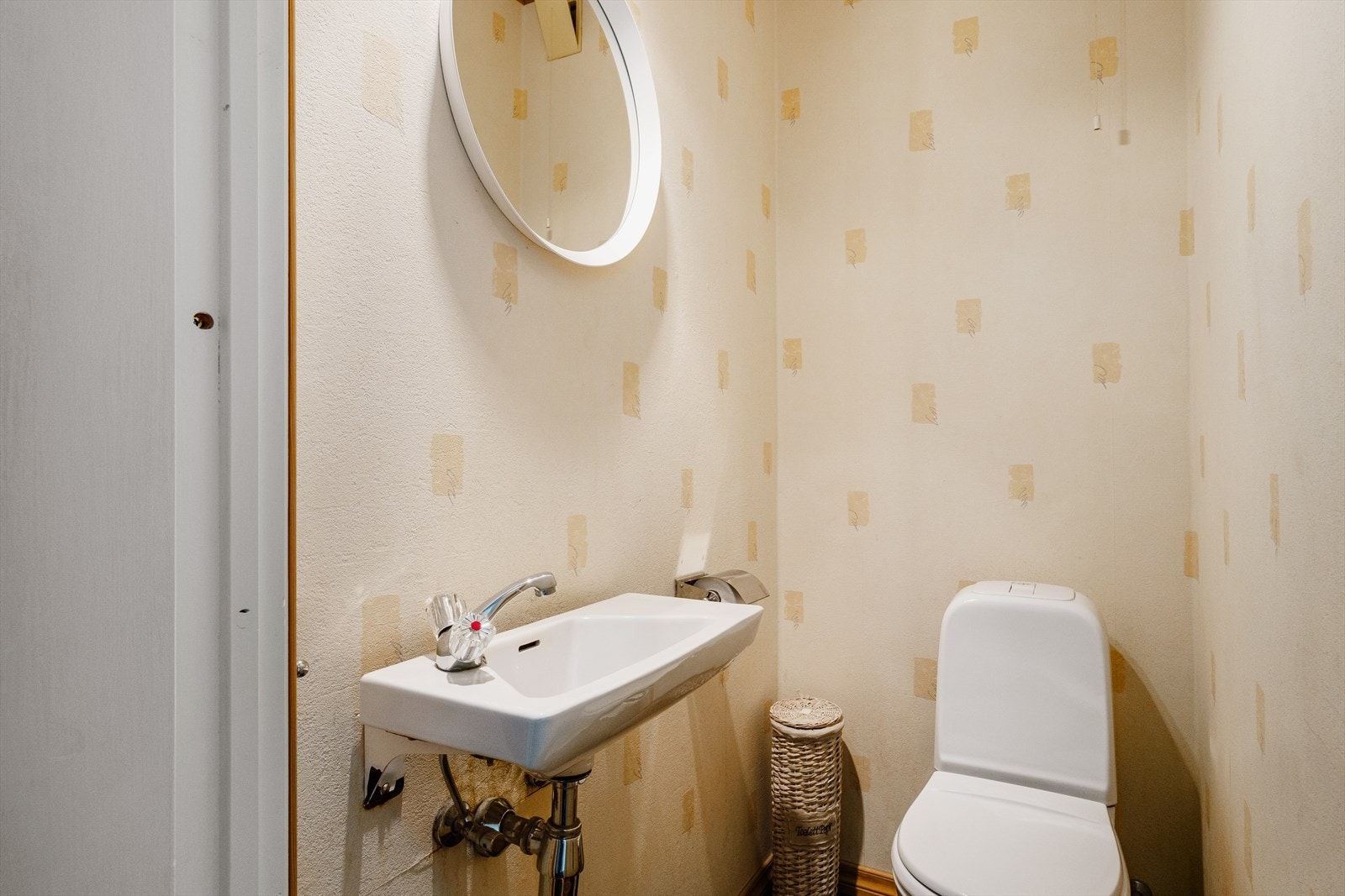 Toalettrom med belegg på gulv og tapet på vegger. Det er toalett og servant. Galleribilde