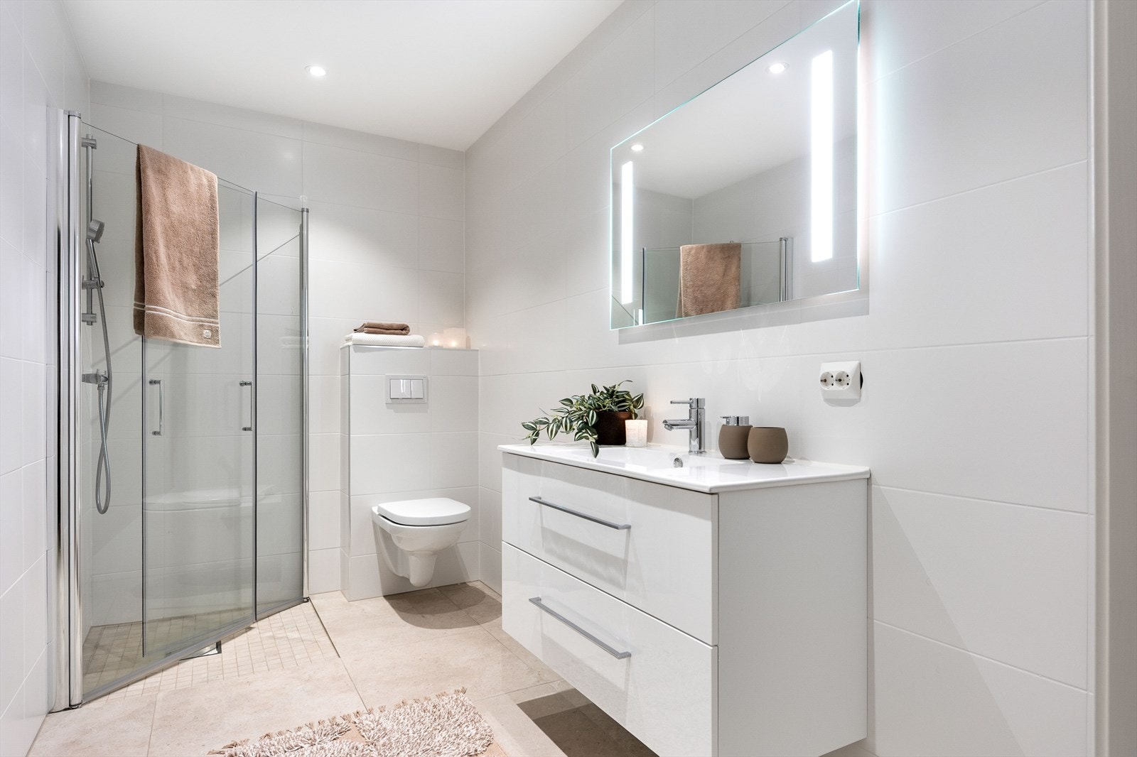 De to badene har lys servantinnredning med skuffer og heldekkende servantplate, samt speil med integrert belysning. Innfelte downlights i tak. Galleribilde