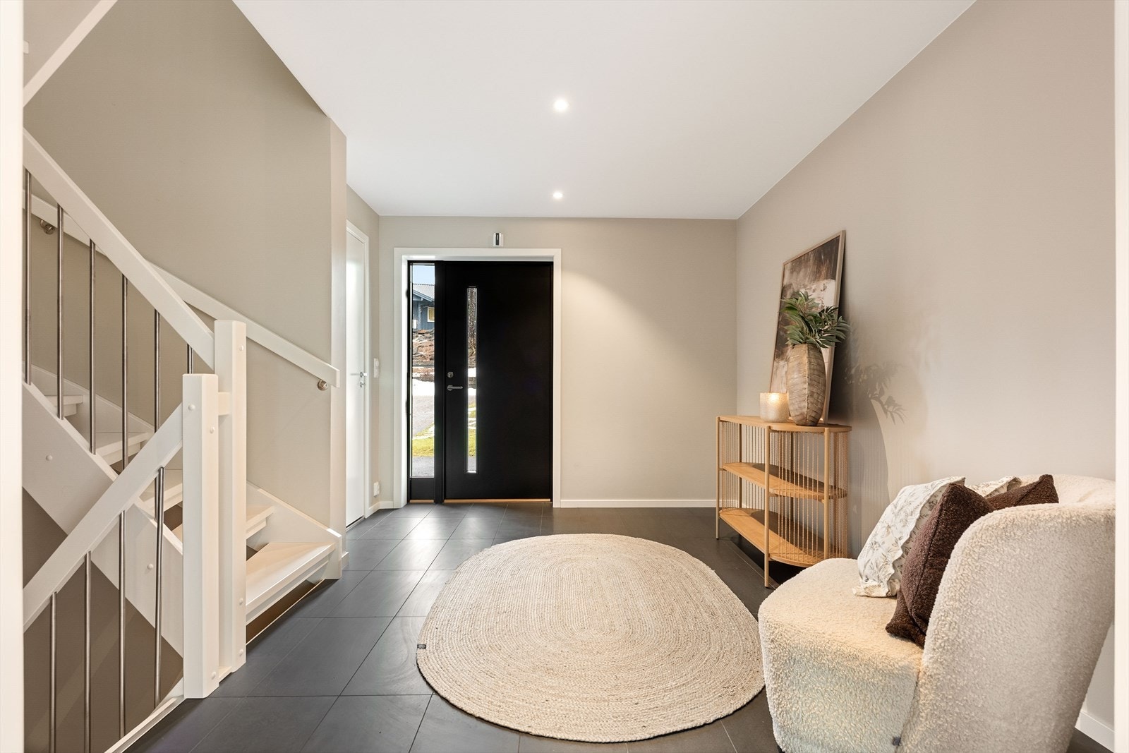 Her er det god plass til oppbevaringsmøblement for sko- og yttertøy. Pen, moderne ytterdør i mørk utførelse med isolerglass og sideglassfelt. Galleribilde