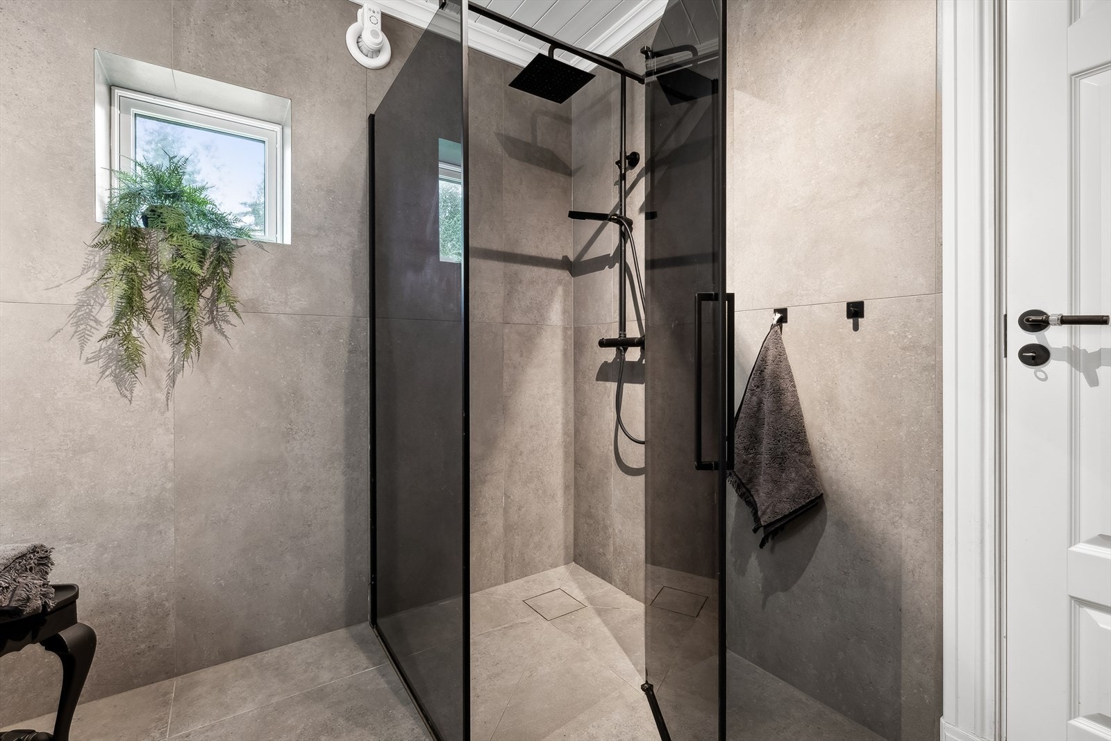 Badet er innredet med dusjhjørne med dører i sotet glass Galleribilde