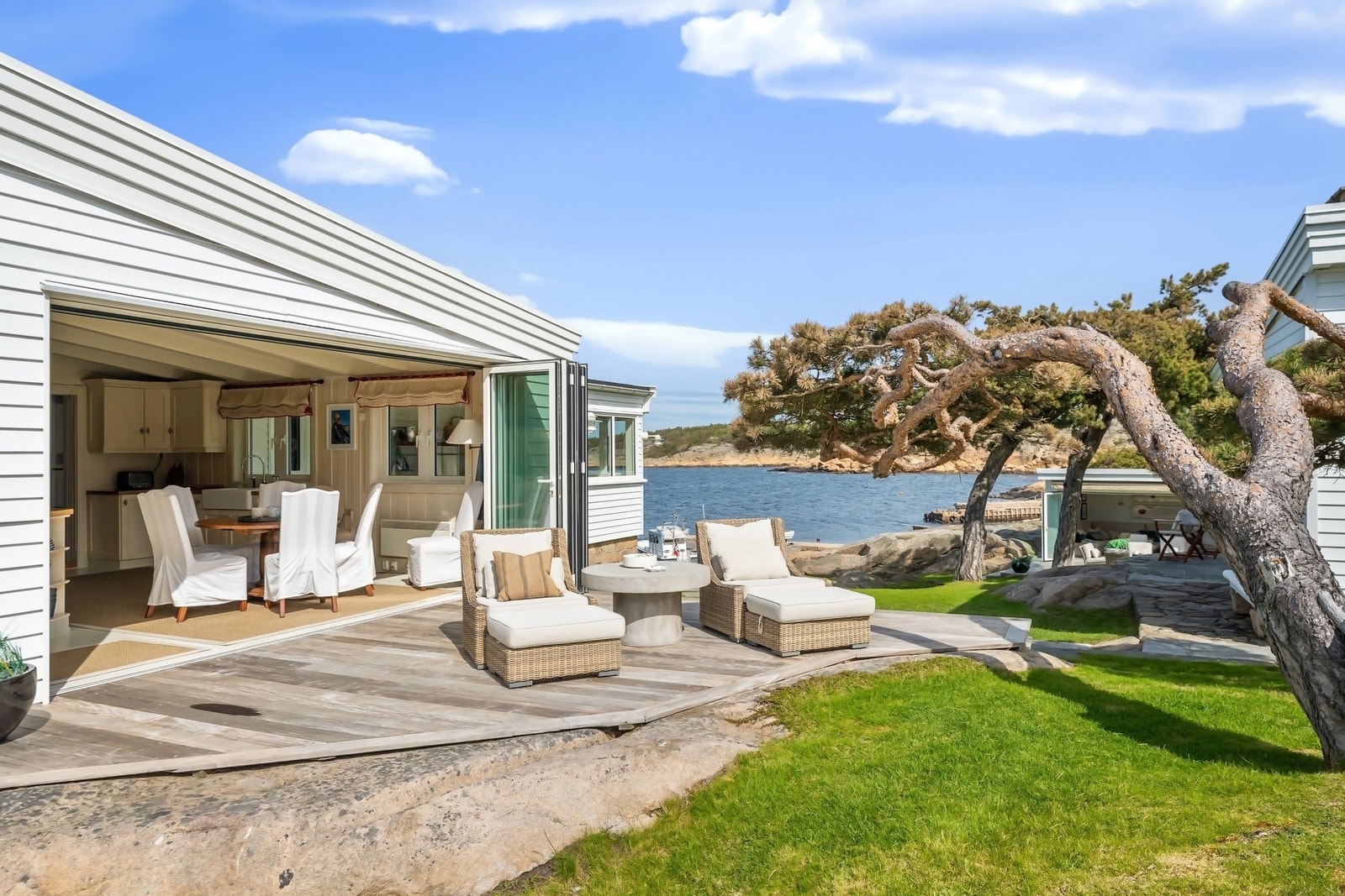 Fra kjøkken er det store skyvedører ut mot et lunt terrasseområde beliggende i le for sjø og vind. Galleribilde