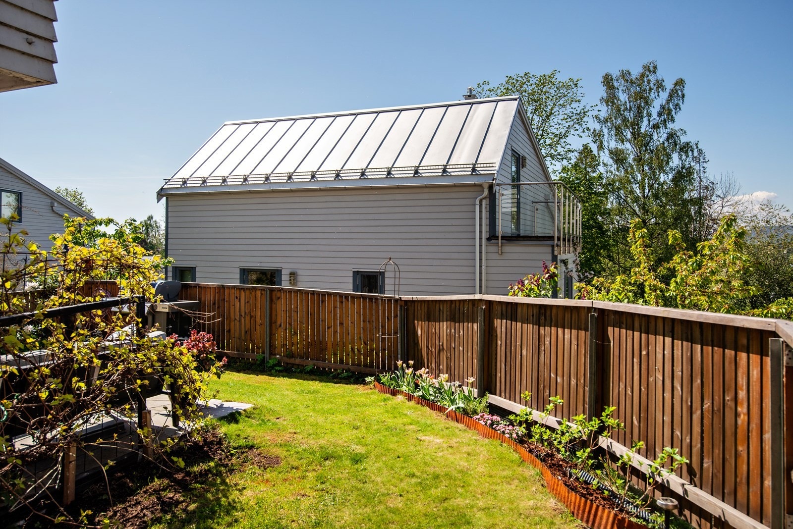 Inngjerdet hage, opparbeidet med gressplen, prydbusker og blomsterbed Galleribilde