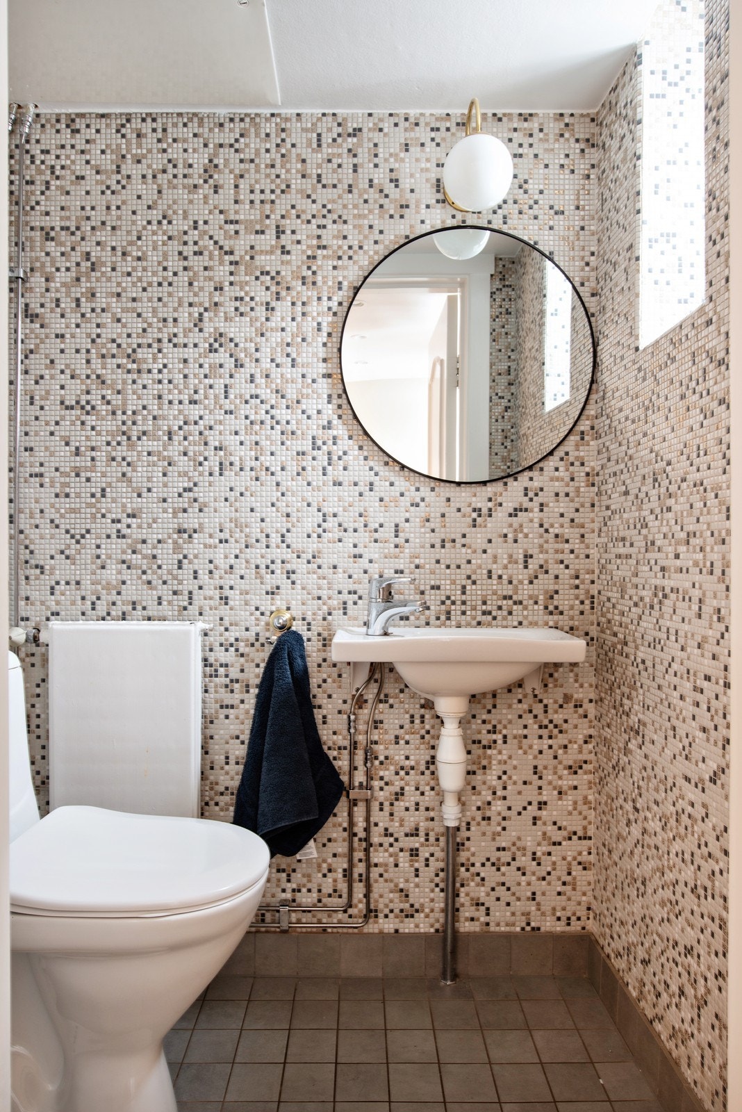 Helfliset toalettrom i underetasje, innredet med toalett og vegghengt servant med blandebatteri Galleribilde