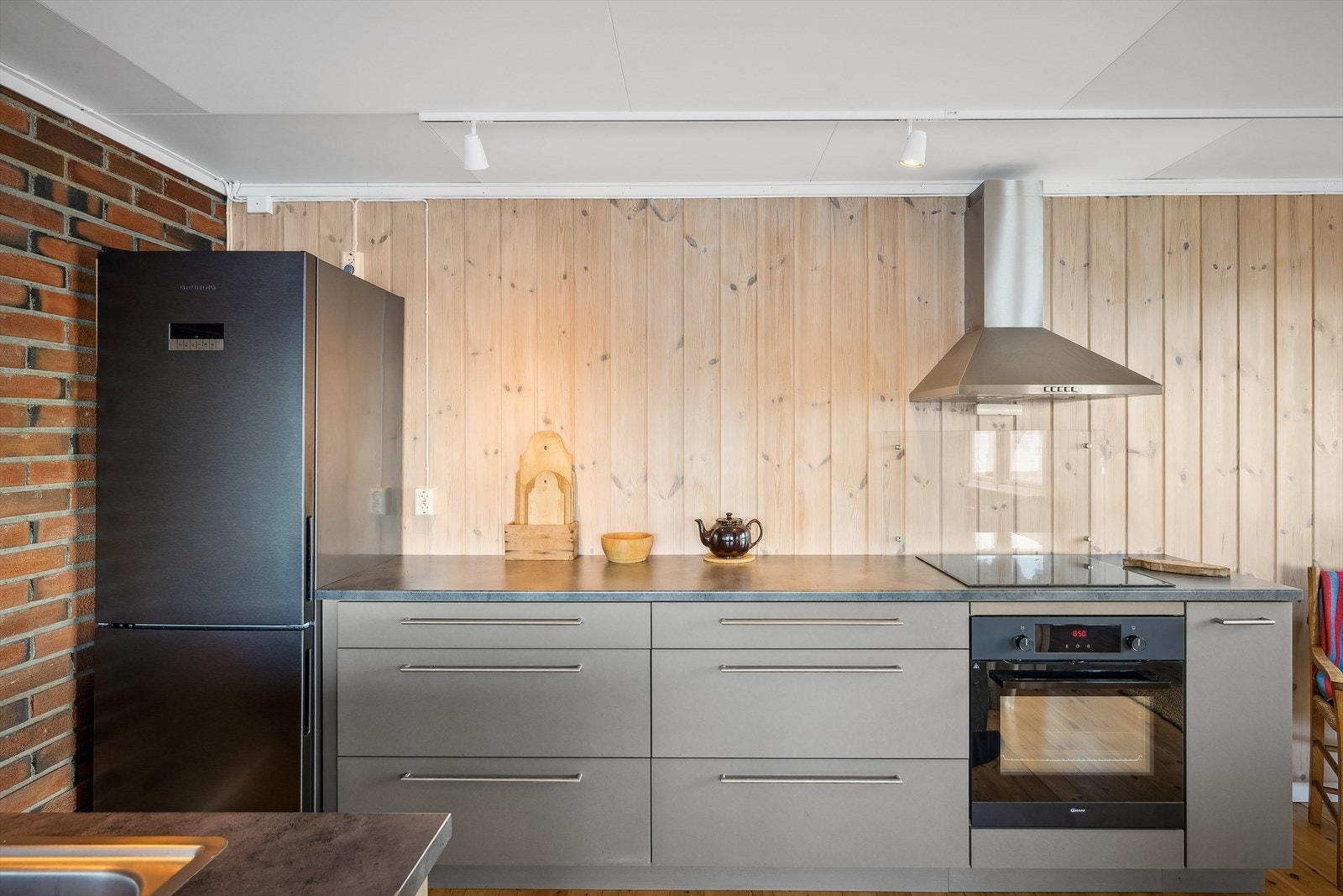 Kjøkkenet har en smakfull innredning med glatte fronter og benkeplate i laminat, utstyrt med oppvaskkum og skyllekum i rustfritt stål. Galleribilde