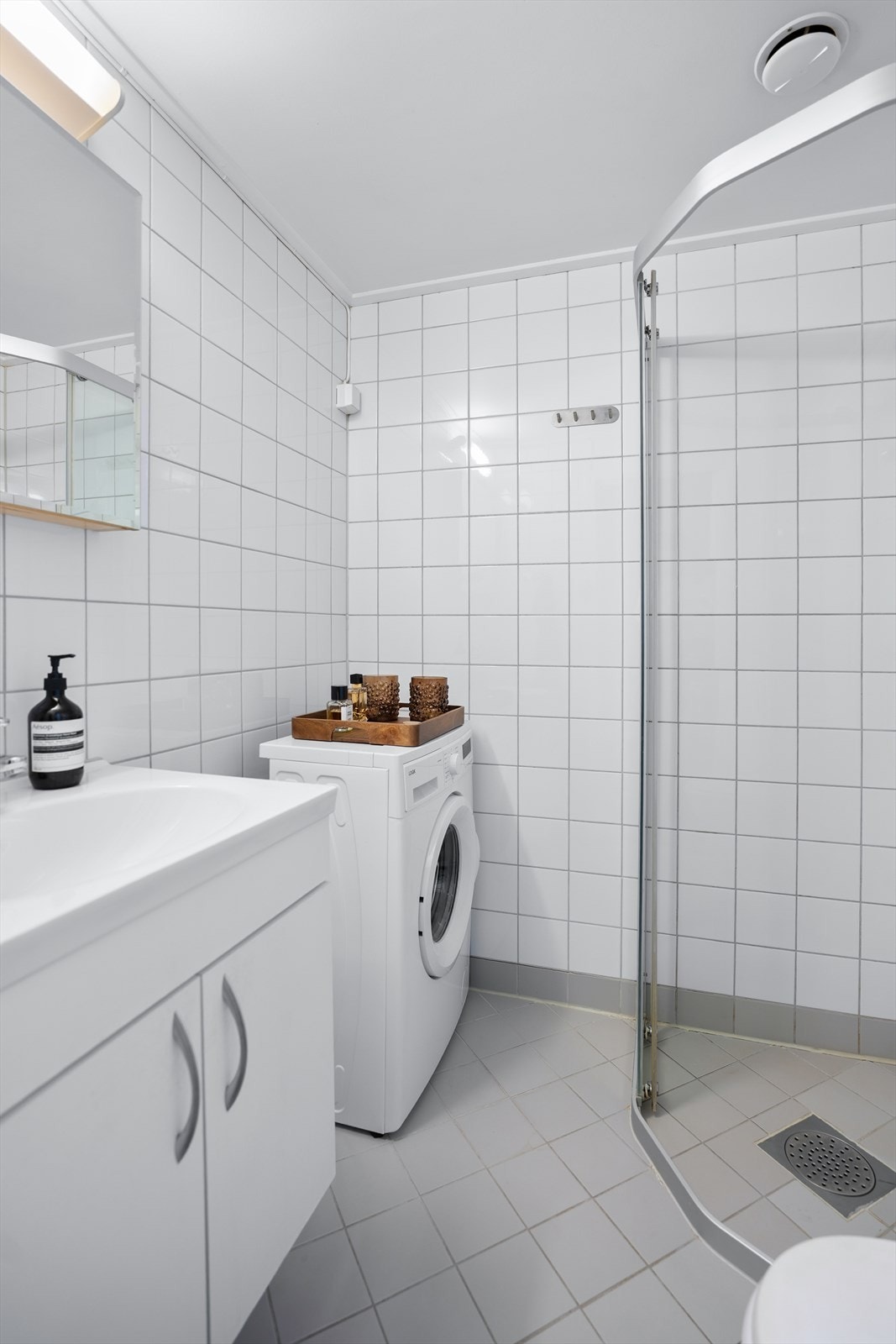 Videre er det dusjhjørne med glassdører og veggmontert dusjarmatur. Galleribilde