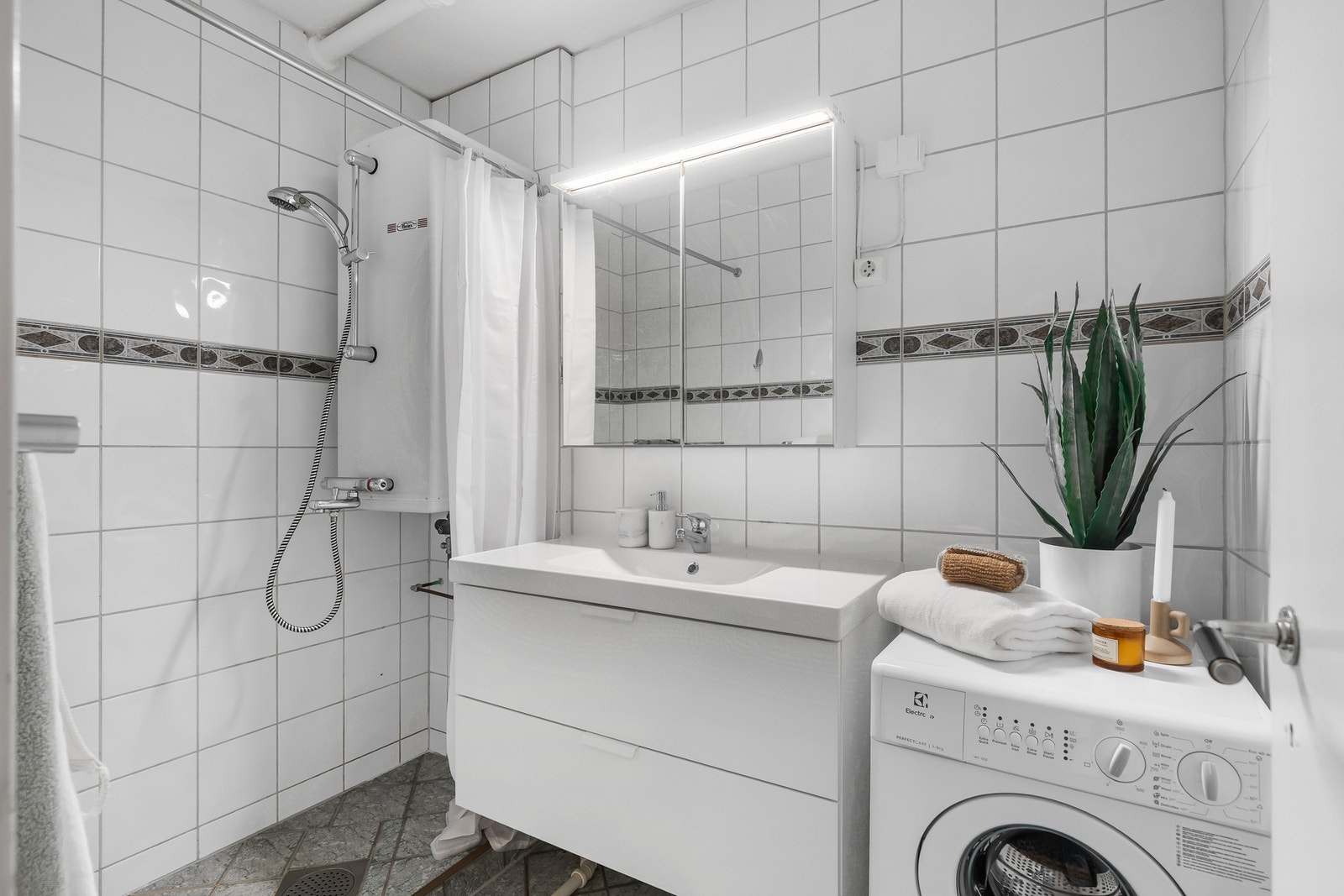 Lyst, flislagt bad med opplegg for vaskemaskin. Galleribilde