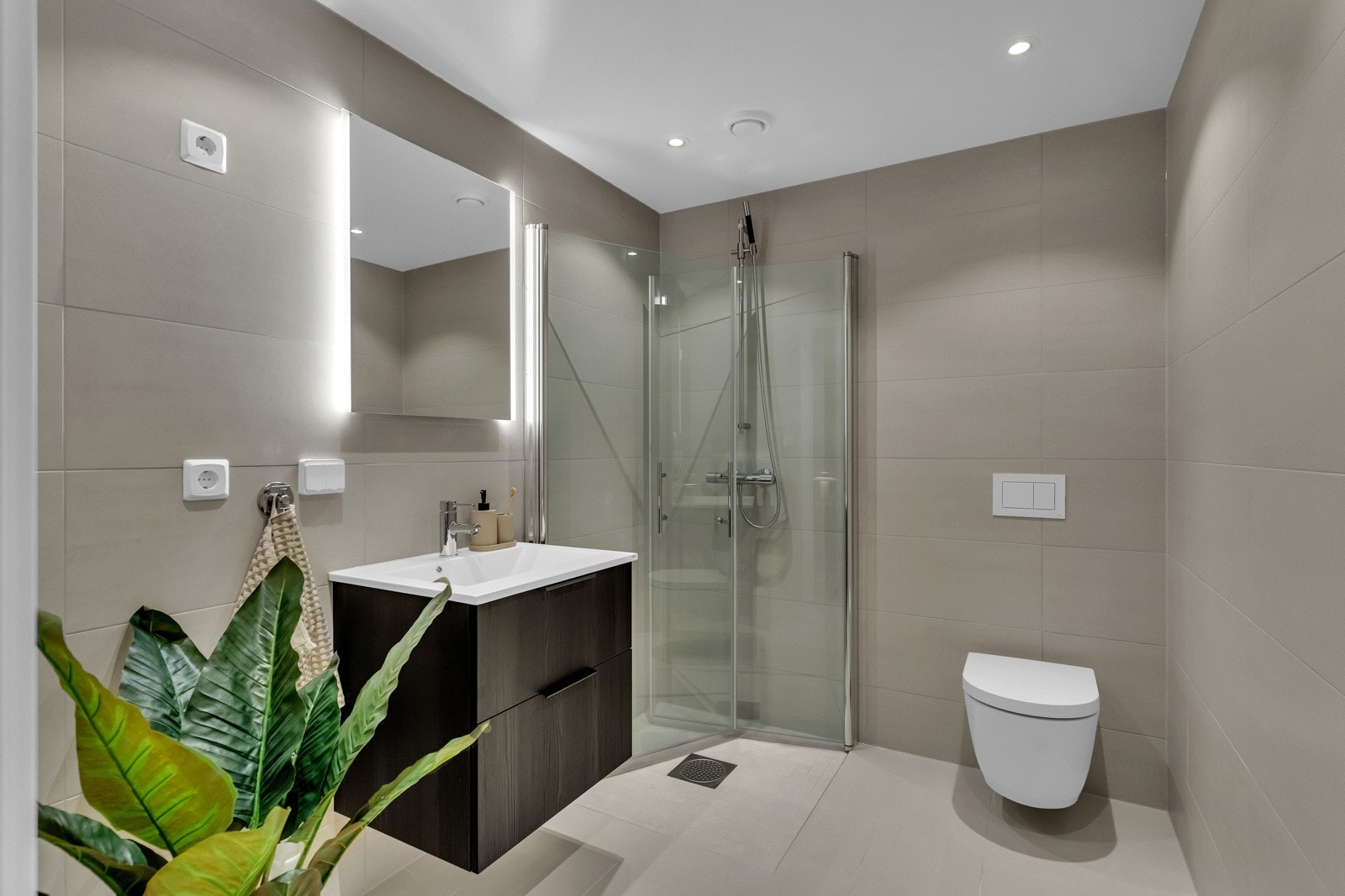 Bad 2 har samme gjennomgående stil med sandfargede fliser og moderne detaljer som veggmontert toalett og dusjarmatur i krom. Det er også opplegg for vaskemaskin og tørketrommel. Galleribilde