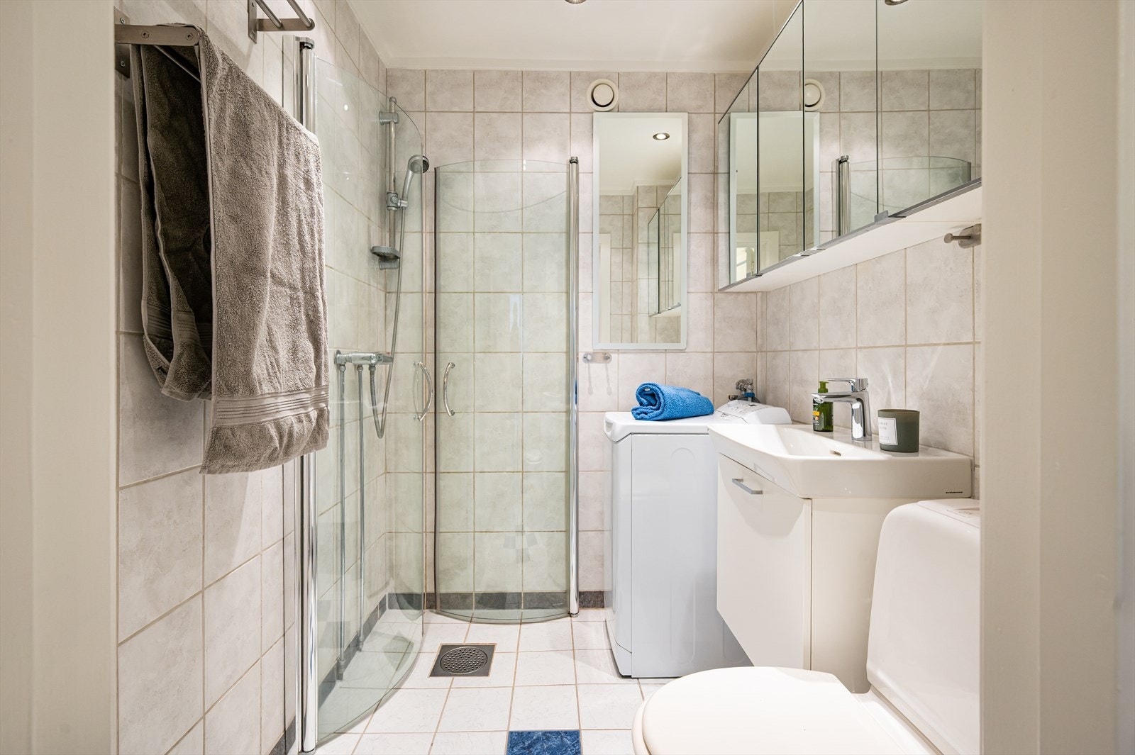 Badet er innredet med klosett, servant nedfelt i innredning, speilskap og dusjhjørne med svingbare glassdører. Det er opplegg for vaskemaskin. Galleribilde