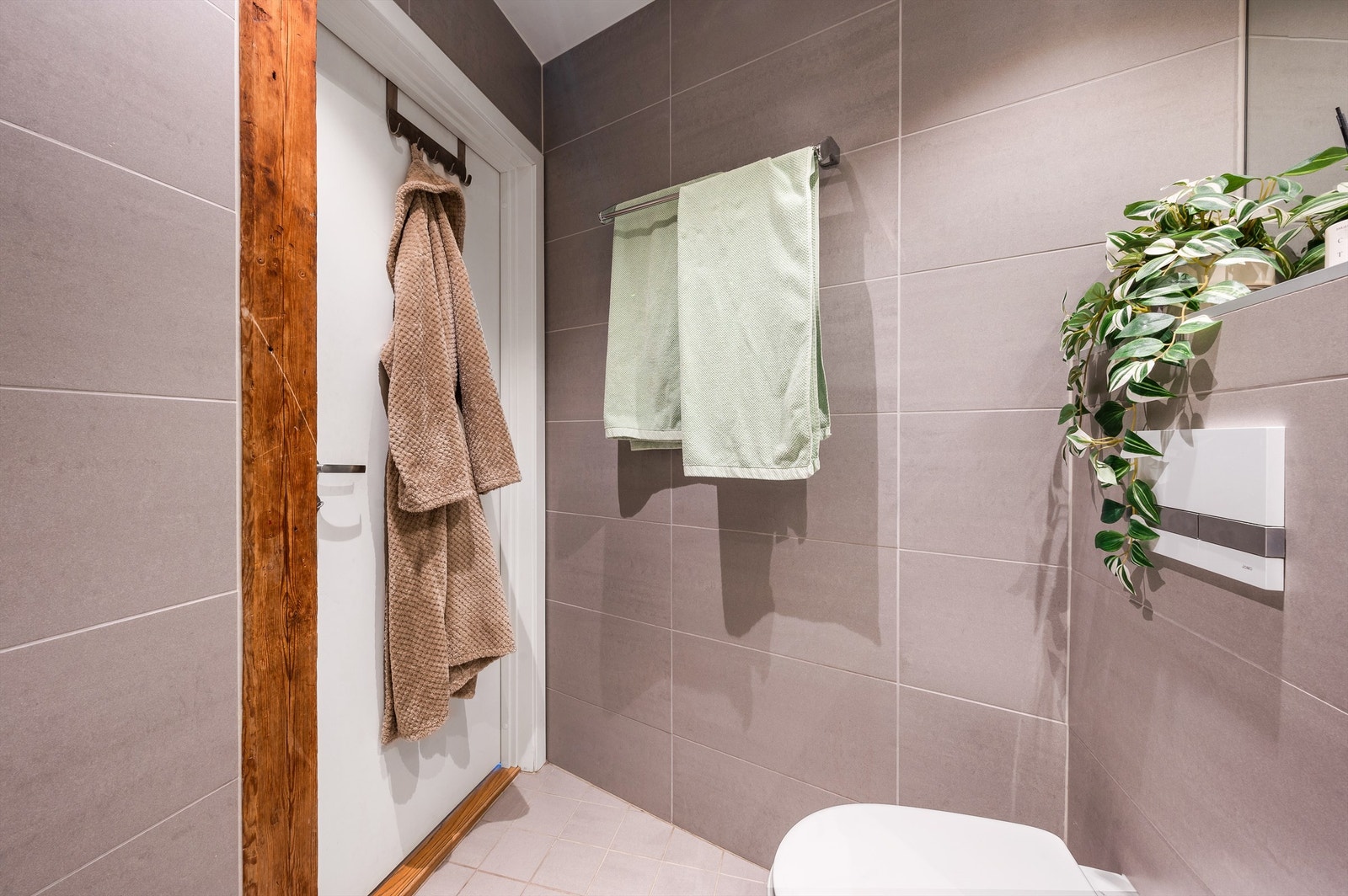 Innredningen består av vegghengt toalett, servant med innredning, innfelt speil og dusjhjørne med svingbare glassdører. Galleribilde