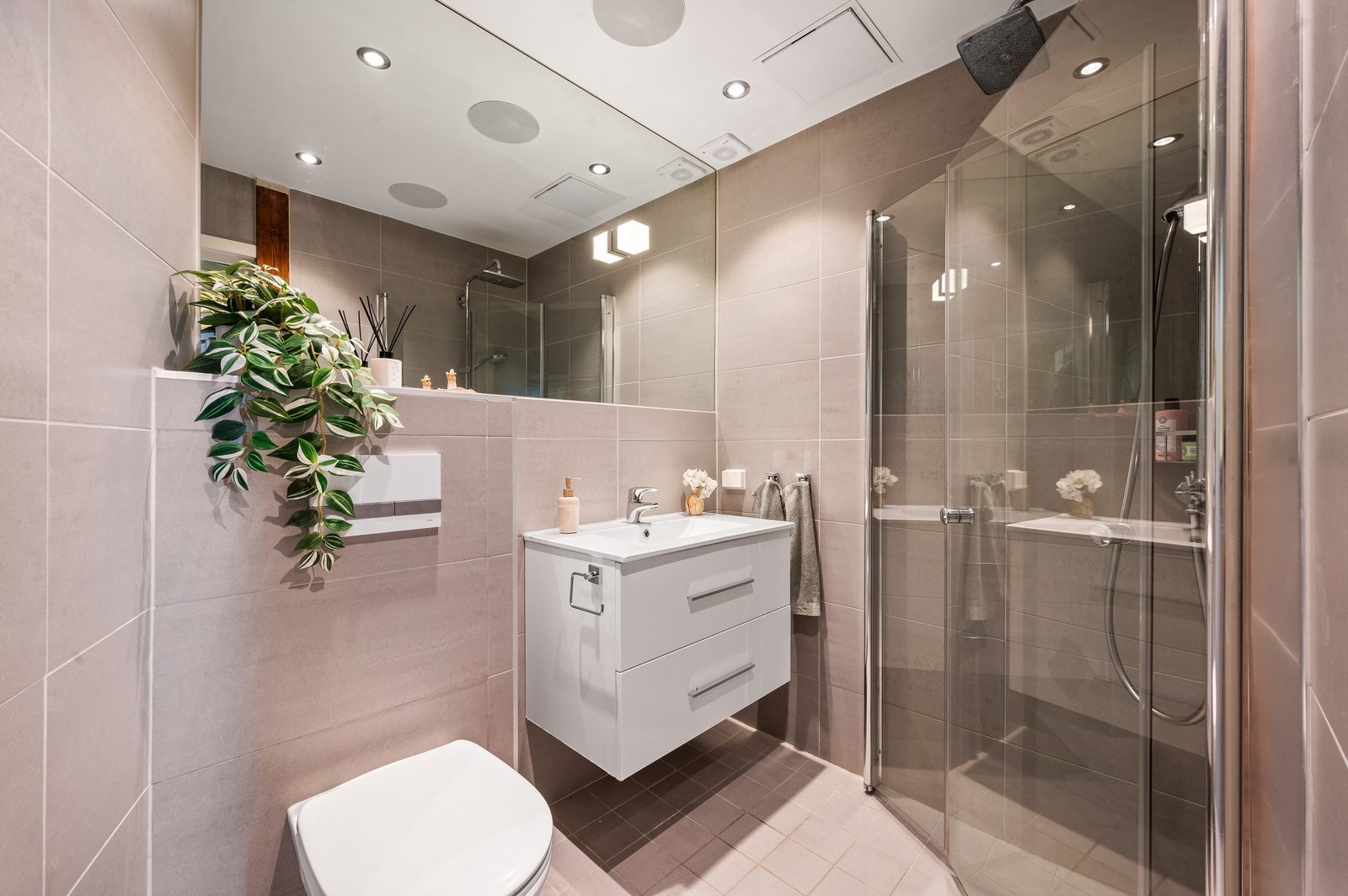 Delikat, flislagt bad fra 2015 med downlights i himlingen og varme i gulv for en lun start på dagen. Galleribilde