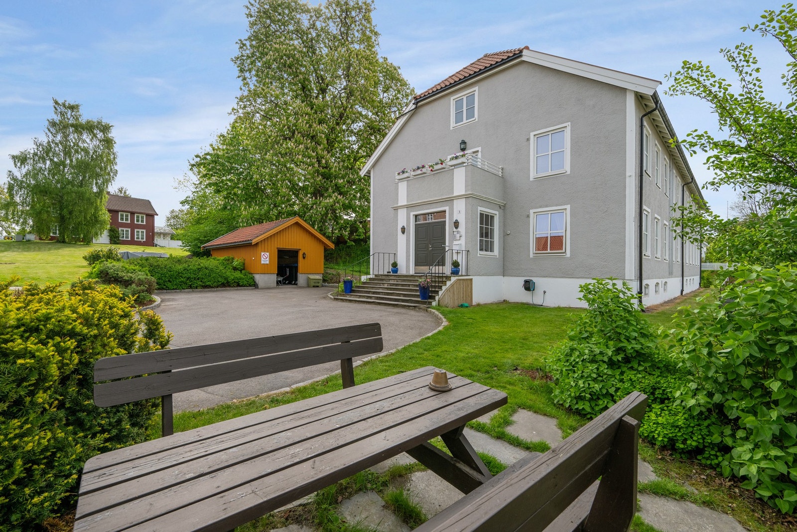 Borettslaget har flere fine uteplasser - her ser vi en hyggelig benk på borettslaget tomt. I tillegg er det felles balkong i 2. etasje som vi ser i bakgrunn. Galleribilde