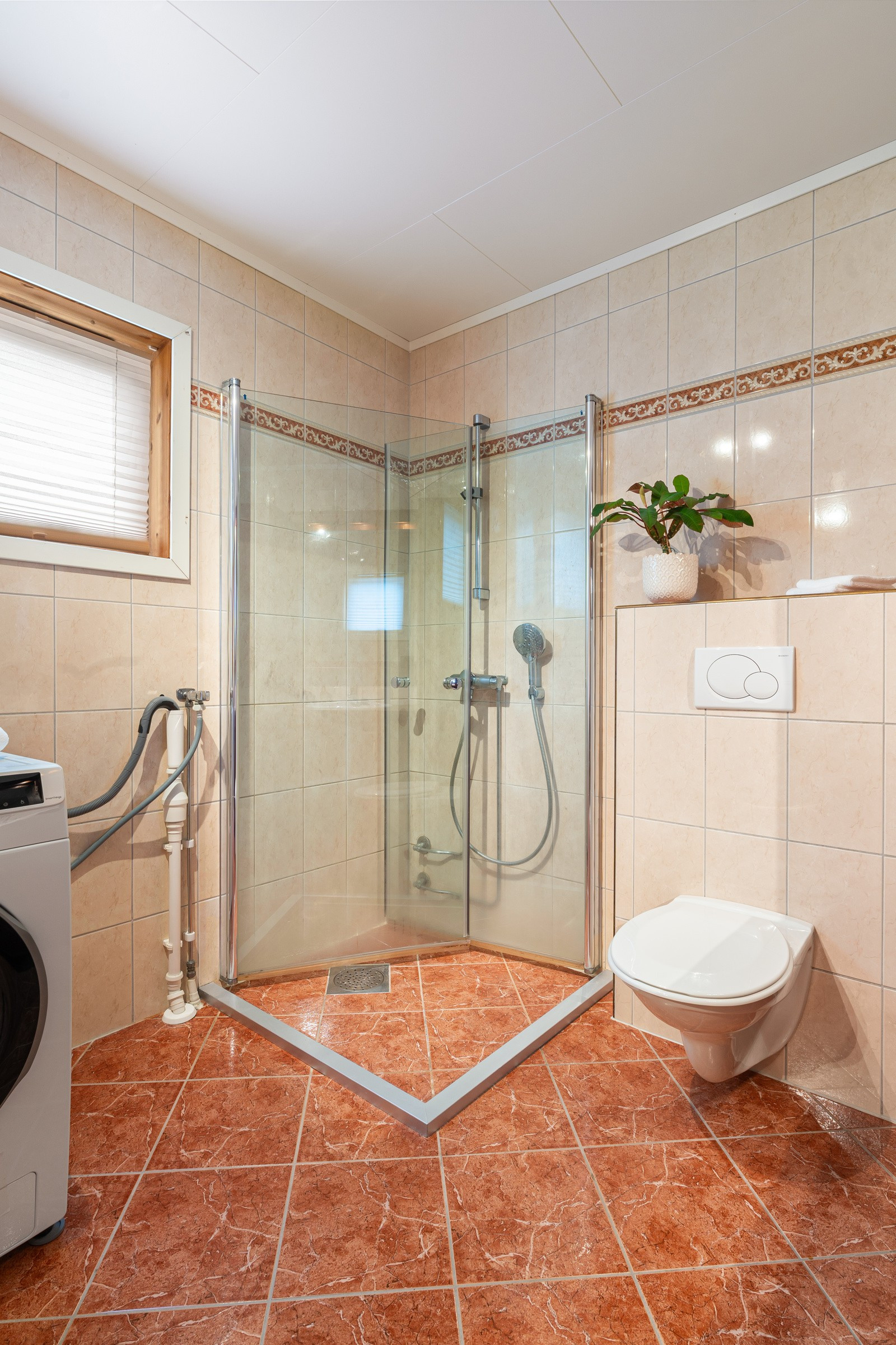 Badet er utstyrt med dusjhjørne, toalett, innredning med oppbevaringsplass og opplegg for vaskemaskin.