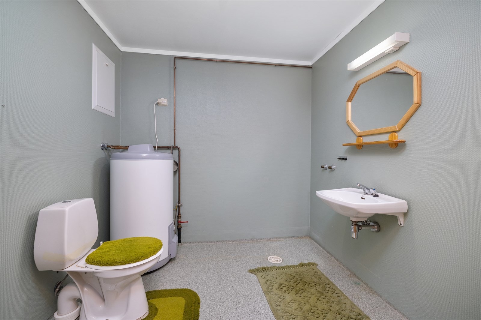 Det er montert frittstående toalett, servant og røropplegg for dusj. Galleribilde