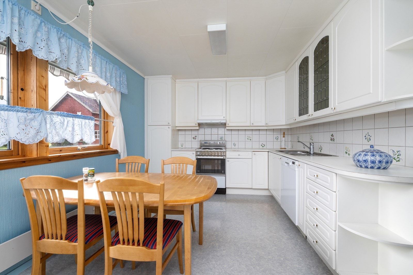 Kjøkken med hvite profilerte malte/laminerte fronter i tre/trefiber, to dører med blyglass fylling. Laminat benkeplater og nedfelt stål oppvaskkum/beslag. Integrert oppvaskmaskin. Galleribilde