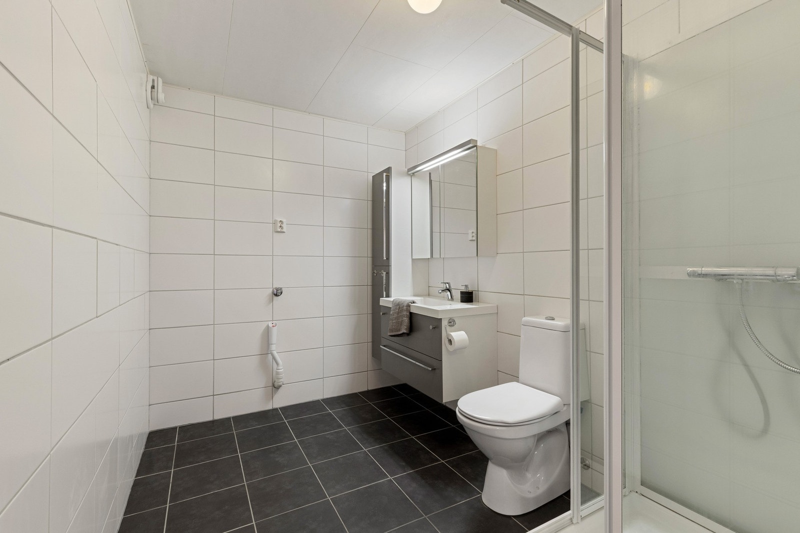 Flott flislagt baderom med opplegg for vaskemaskin. Galleribilde