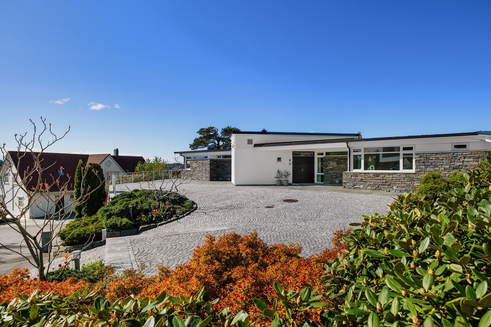 Tomten er pent opparbeidet med brosteiner, skifer og beplantning. Galleribilde