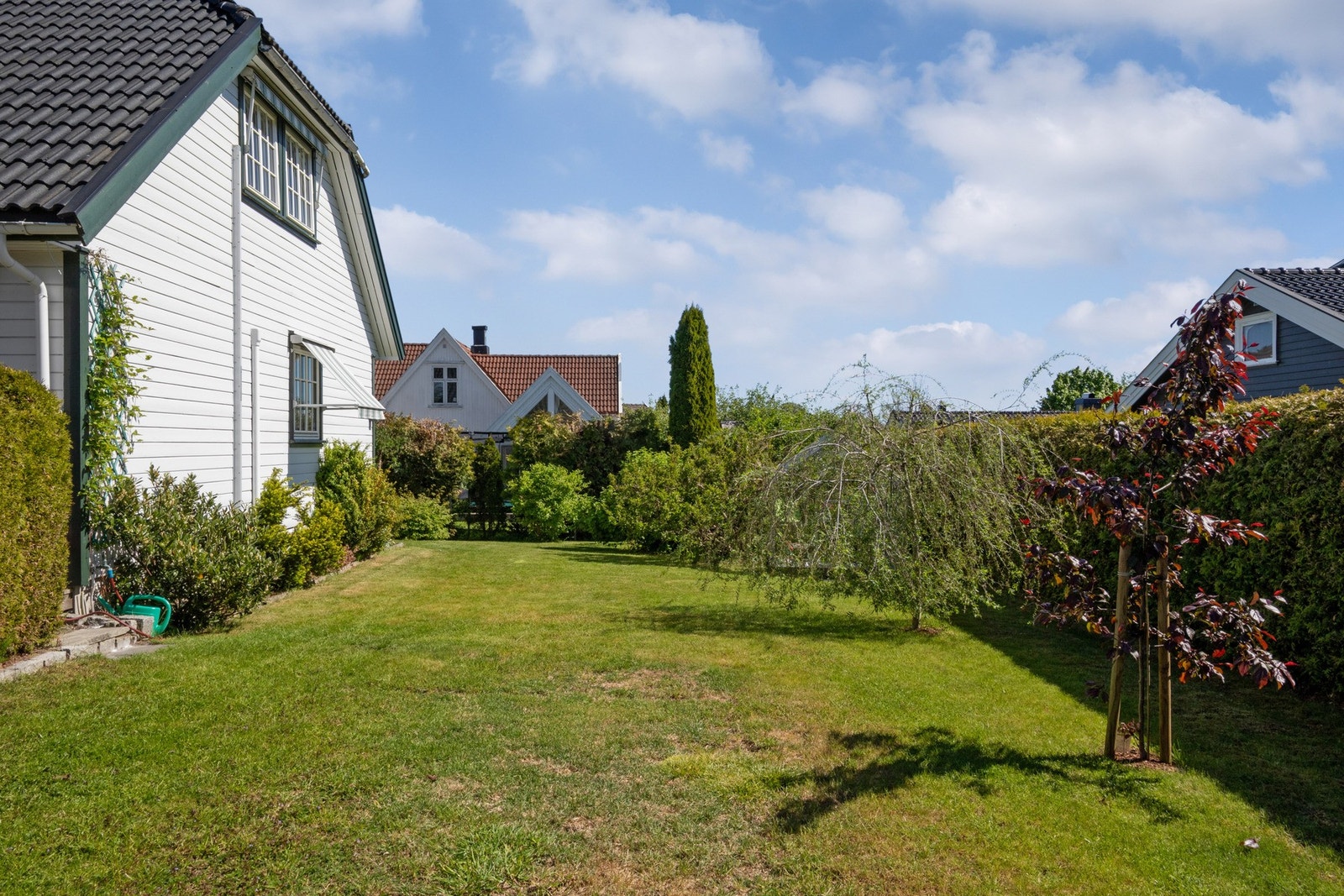 Tomten er svært pent opparbeidet med gressplen, blomsterbed og diverse beplantning Galleribilde