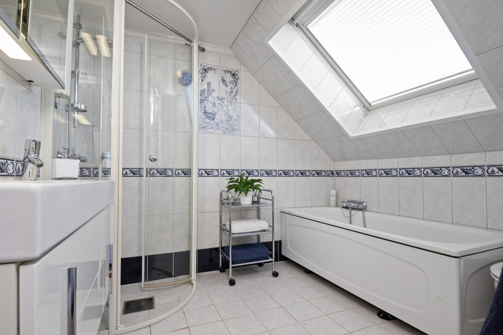 Flislagt bad med gulvvarme utstyrt med dusjhjørne, badekar og innredning med servant Galleribilde