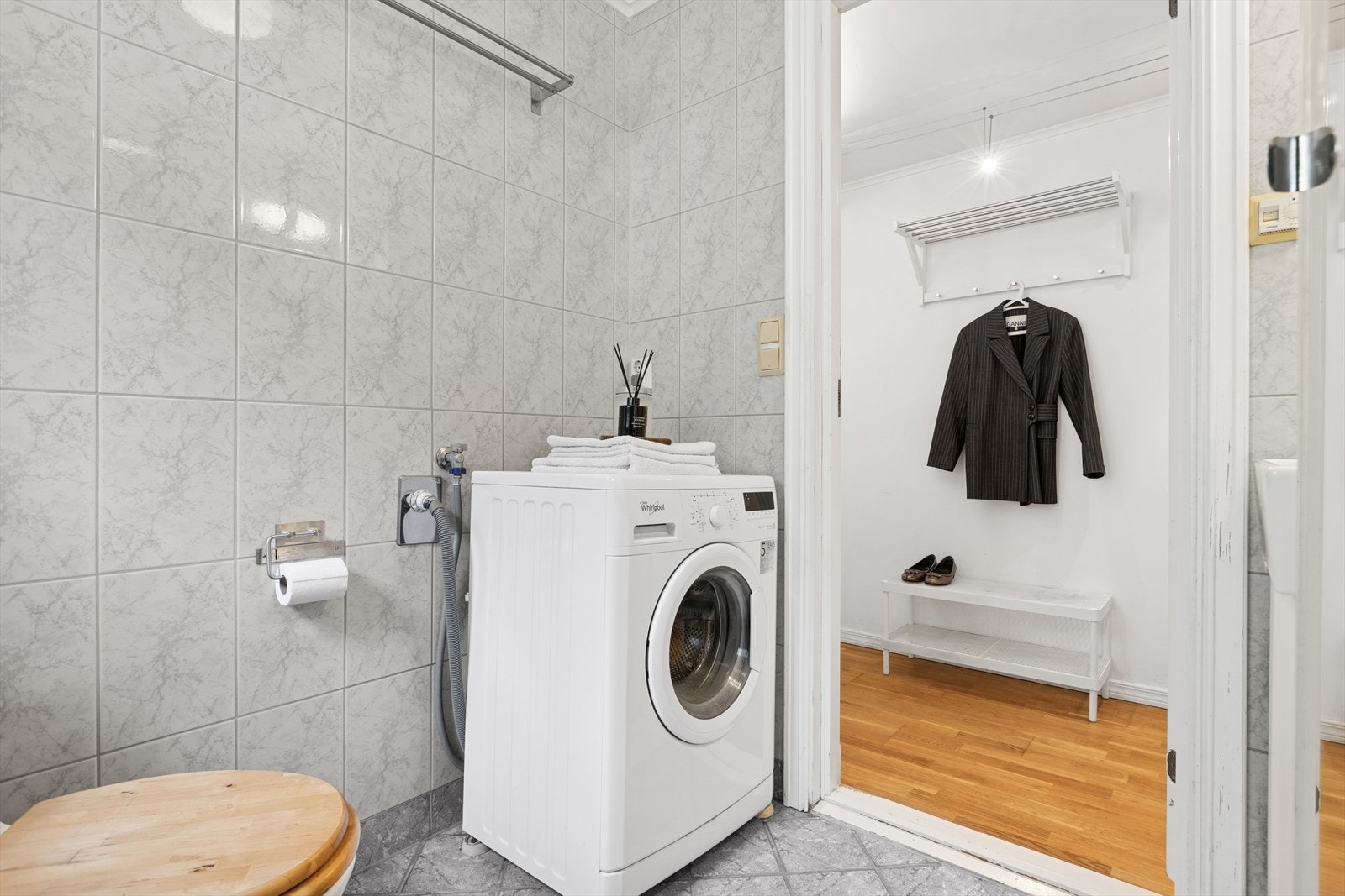 Badet har innredning med servant, røropplegg for vaskemaskin, gulvmontert toalett og dusjgarnityr på vegg. Galleribilde
