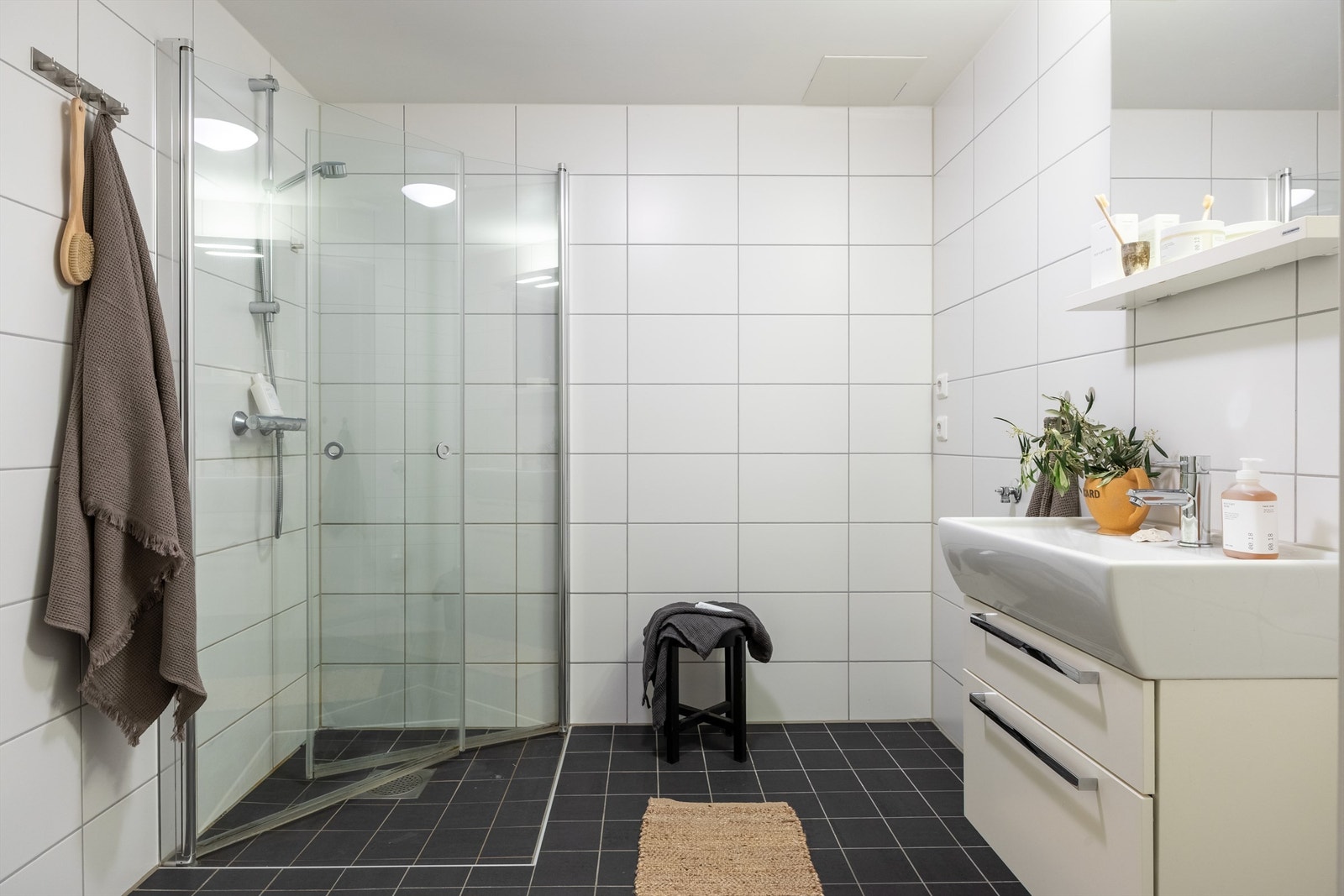 Flislagt bad av god standard m/varmekabler - bestående av vegghengt toalett, dusjarmatur m/glassfronter, servant m/servantskap og opplegg for vaskemaskin. Galleribilde