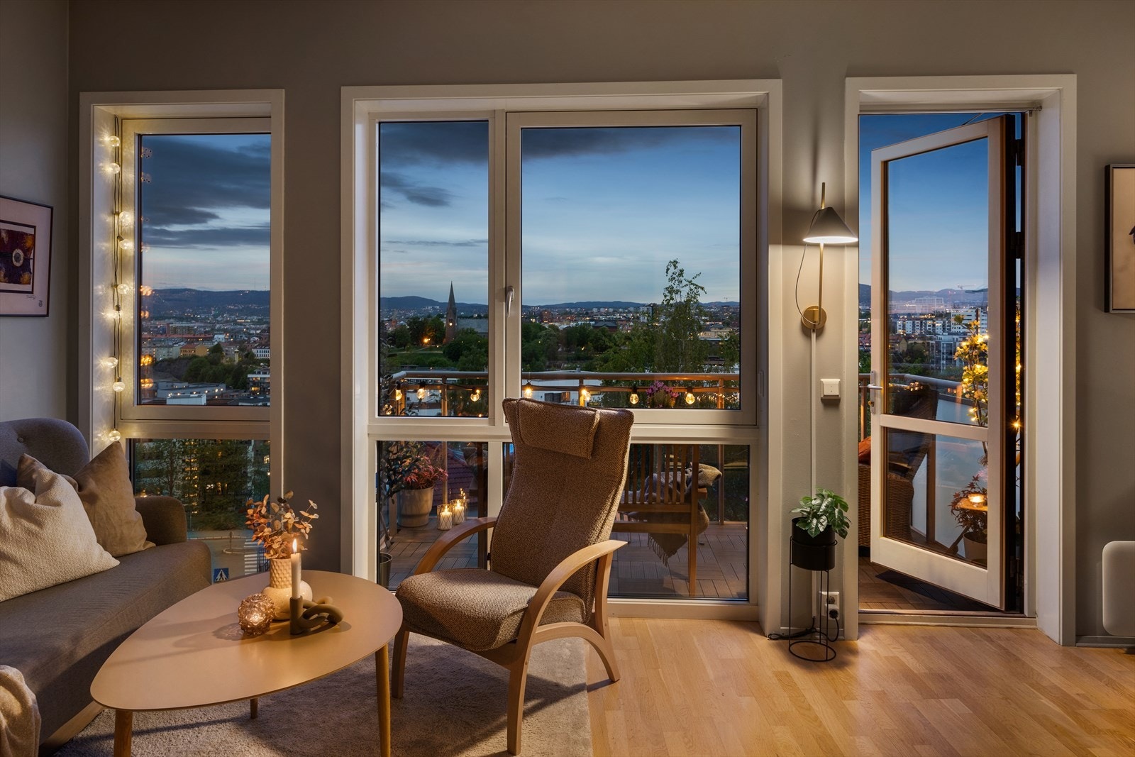 Stemningsfull atmosfære i stuen på kveldstid - lune toner og nydelig utsyn mot byen setter rammen for avslappende kvelder. Galleribilde
