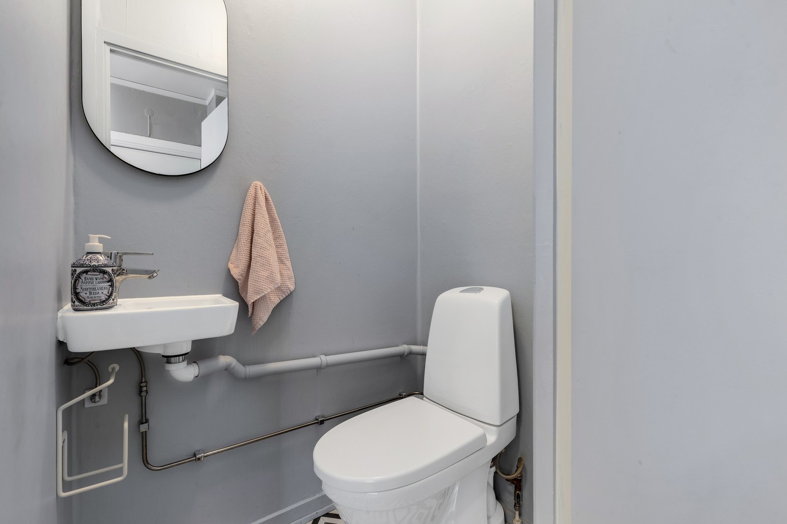 Toalettrom med gulvmontert WC og håndvask. Galleribilde