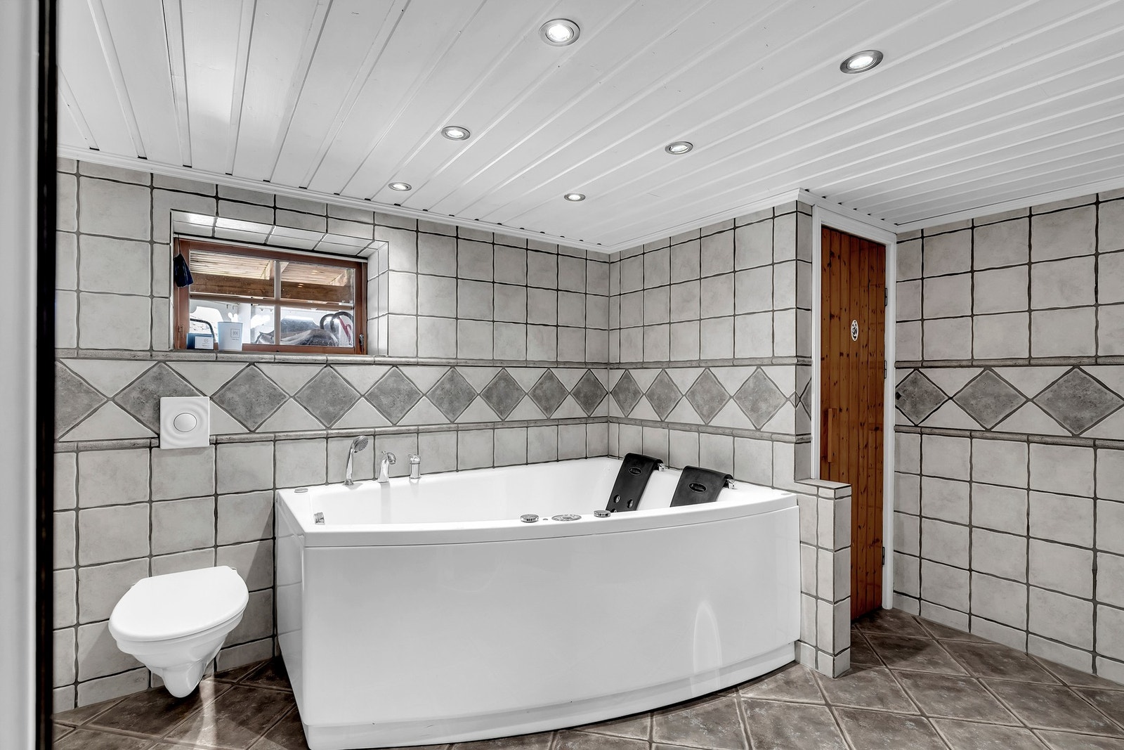 Badet i underetasjen har en innredning som inkluderer servant, vegghengt toalett, badekar og dusjvegger. Galleribilde