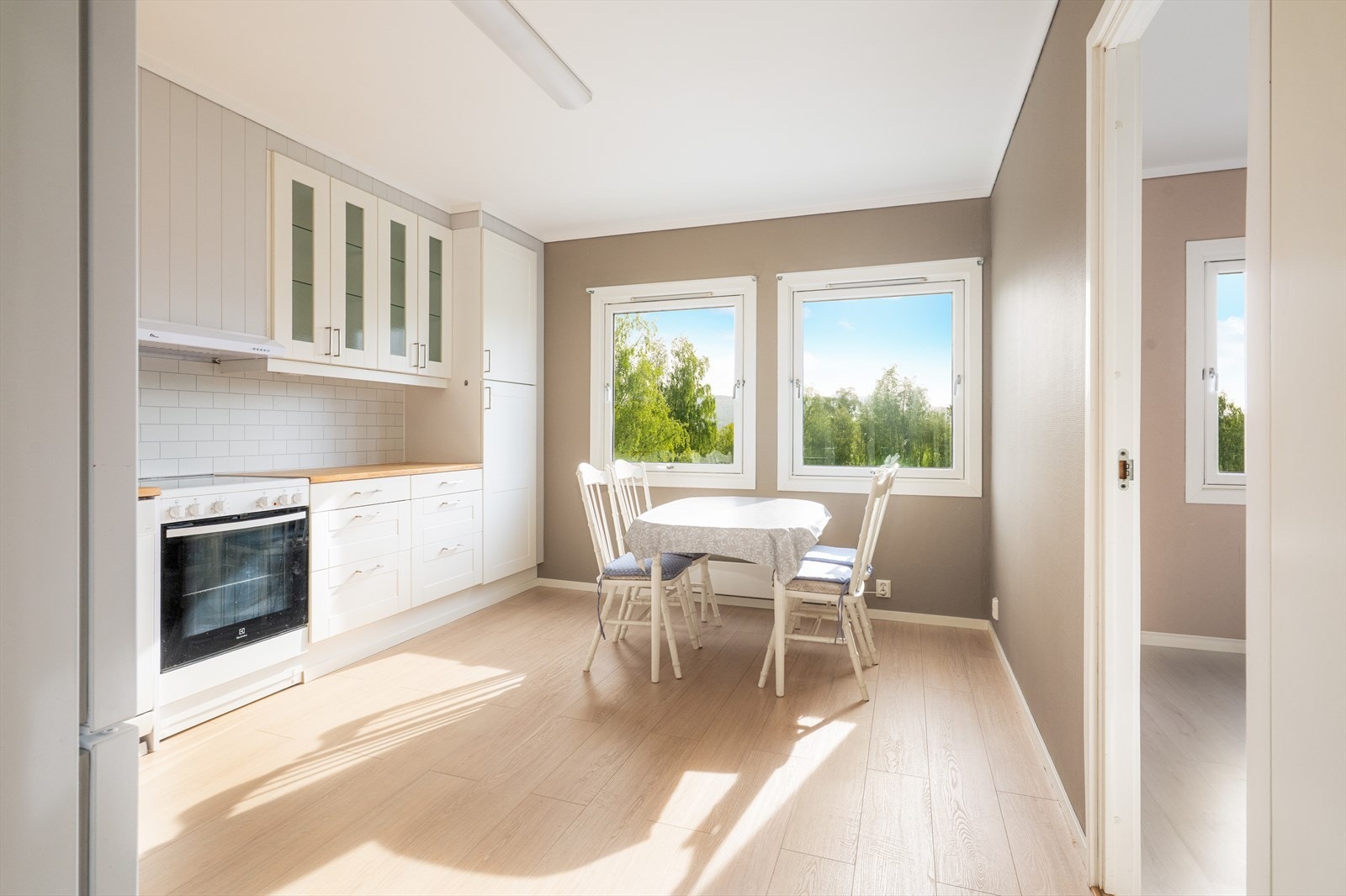 Kjøkkenet har en lys innredning med profilerte fronter og noe glasskap, heltre benkeplate og beskyttelsesplater over kjøkkenbenk. Galleribilde