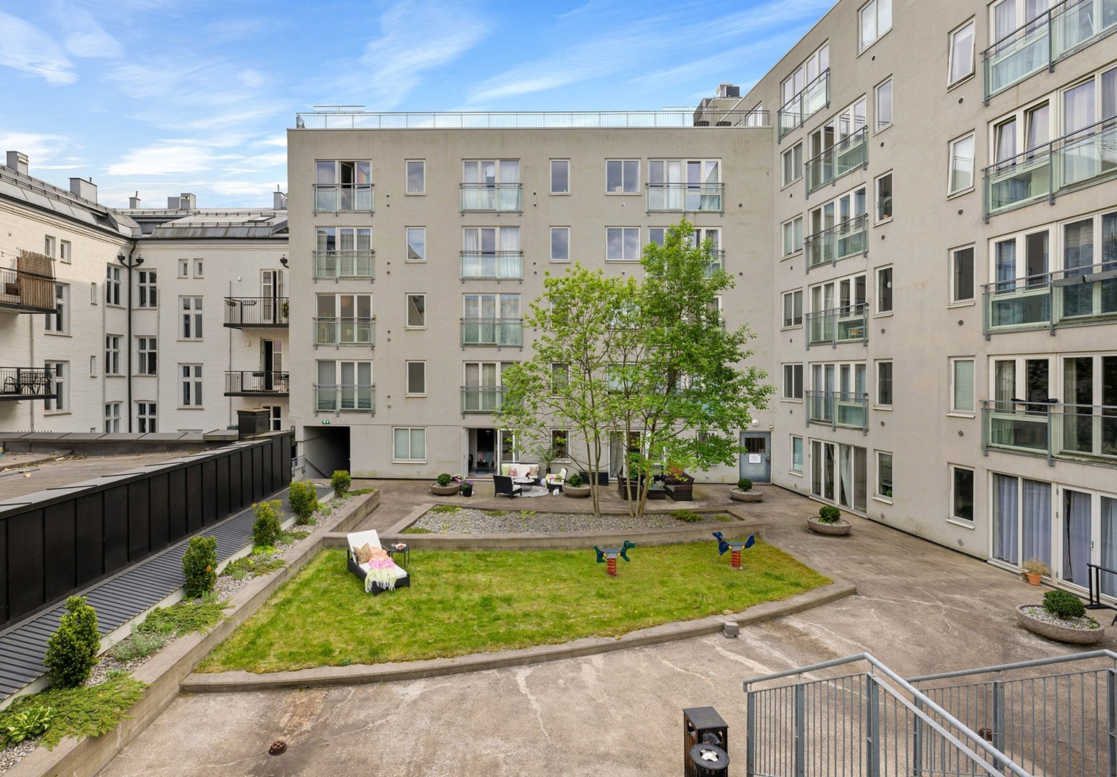 Indre atrium/bakgård er pent opparbeidet i 3 nivåer med blant annet gressplen, treplattinger med hagemøbler, blomsterbed og lekestativ for barn. Galleribilde