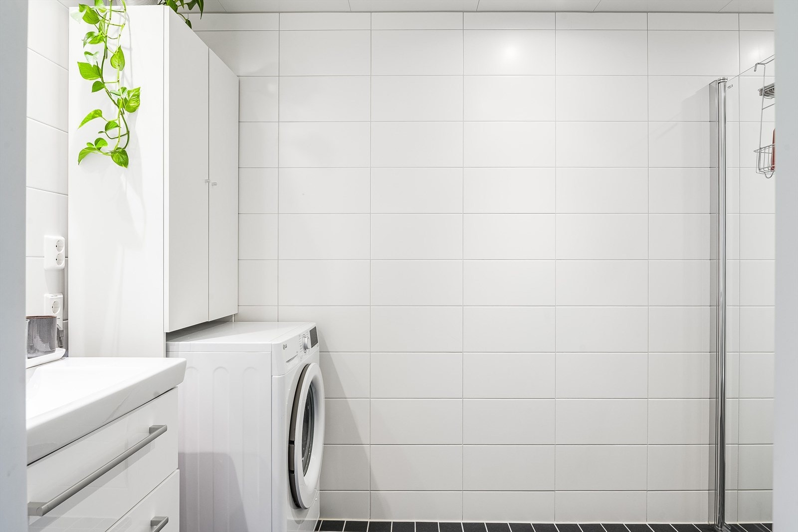 Leiligheten har et lyst og moderne baderom fra byggeåret 2023. Baderommet har mørke fliser på gulv med gulvvarme, hvite fliser på veggene og balansert ventilasjon. Galleribilde
