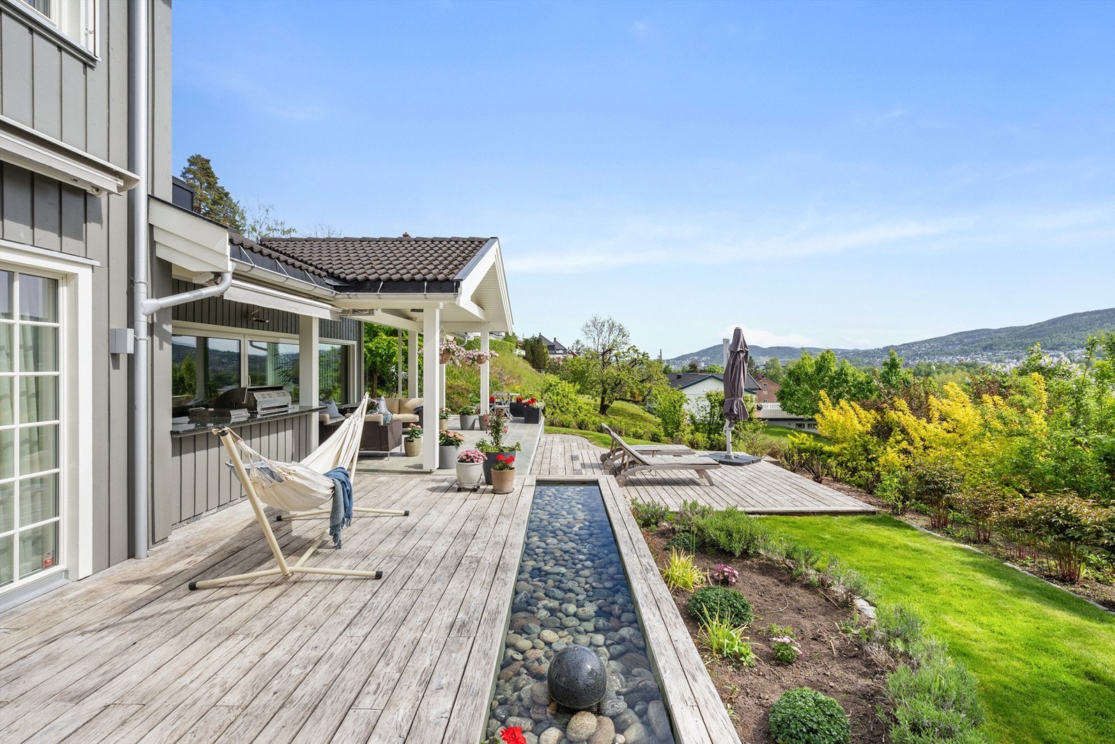 Vannspeil/fuglebad med stein og blomsterkasser langs terrassen Galleribilde