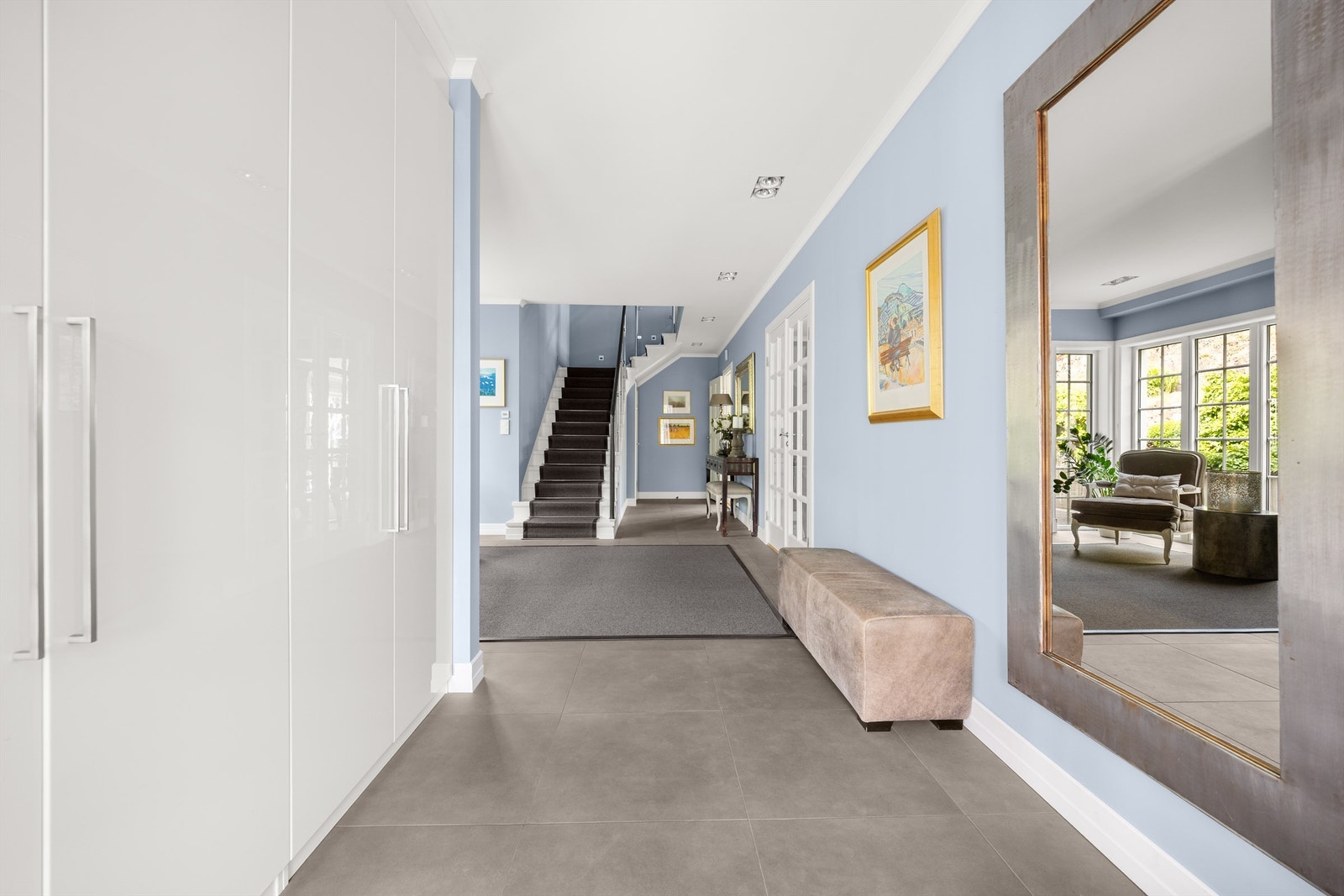 Romslig garderobeløsning med takhøy skapinnredning i hvit samt glatt utførelse - plassert i sidegang Galleribilde