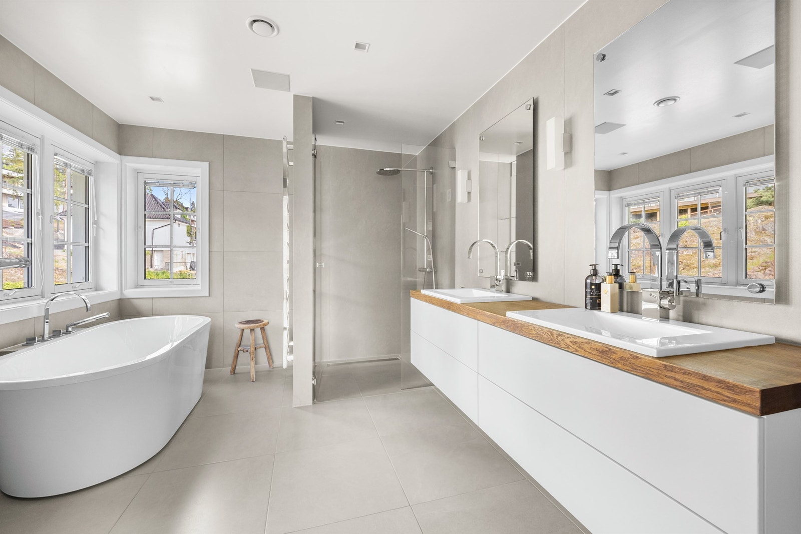 Badet har dusjnisje med veggmontert regnfallsdusj samt dusjvegg av glass Galleribilde