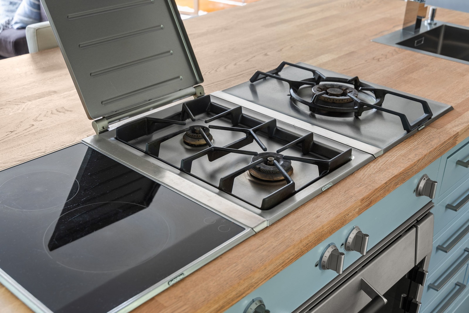 Integrert smal platetopp med induksjon og integrerte koketopper med gassbluss i kjøkkenøy Galleribilde